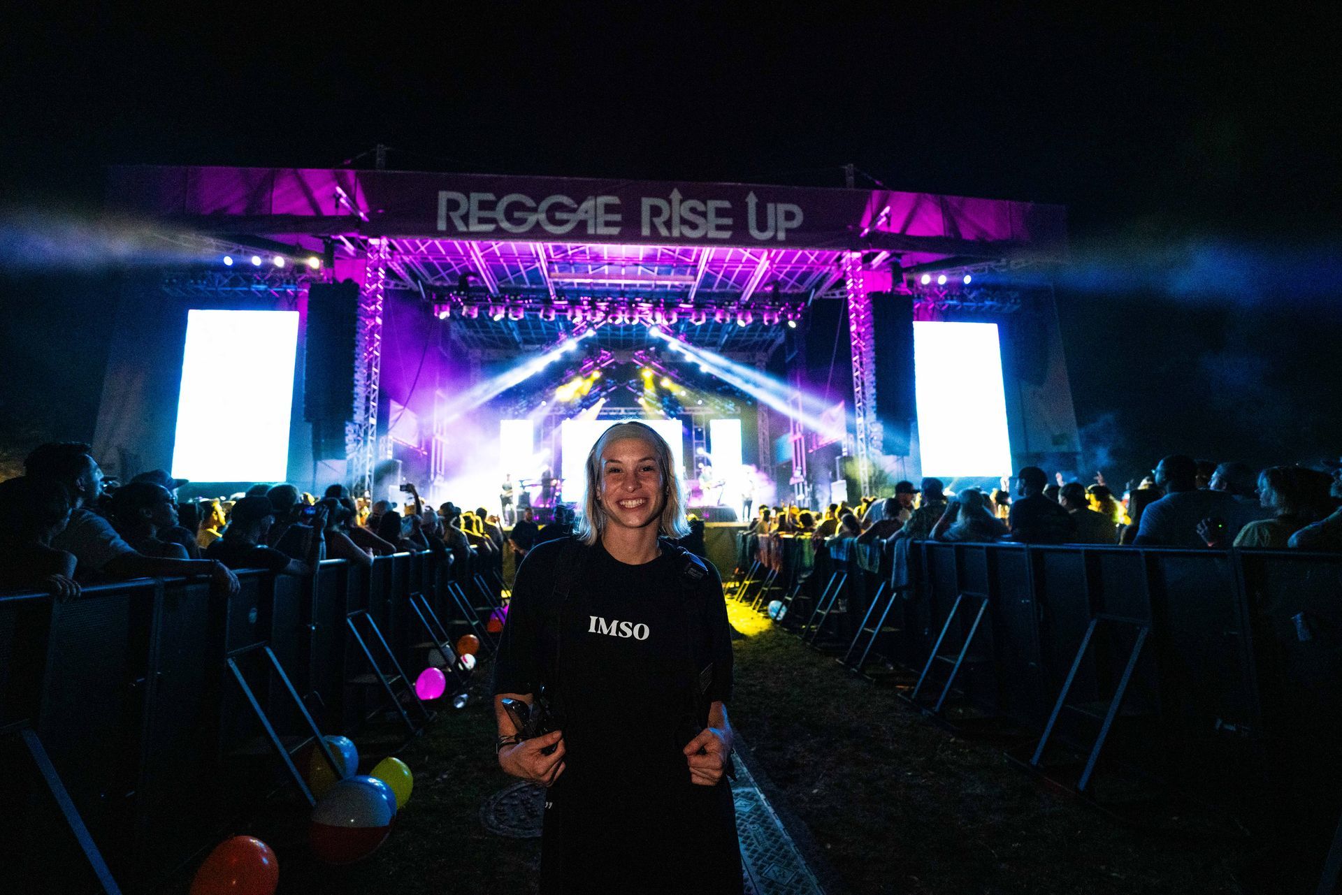A woman is standing in front of a stage at a concert.