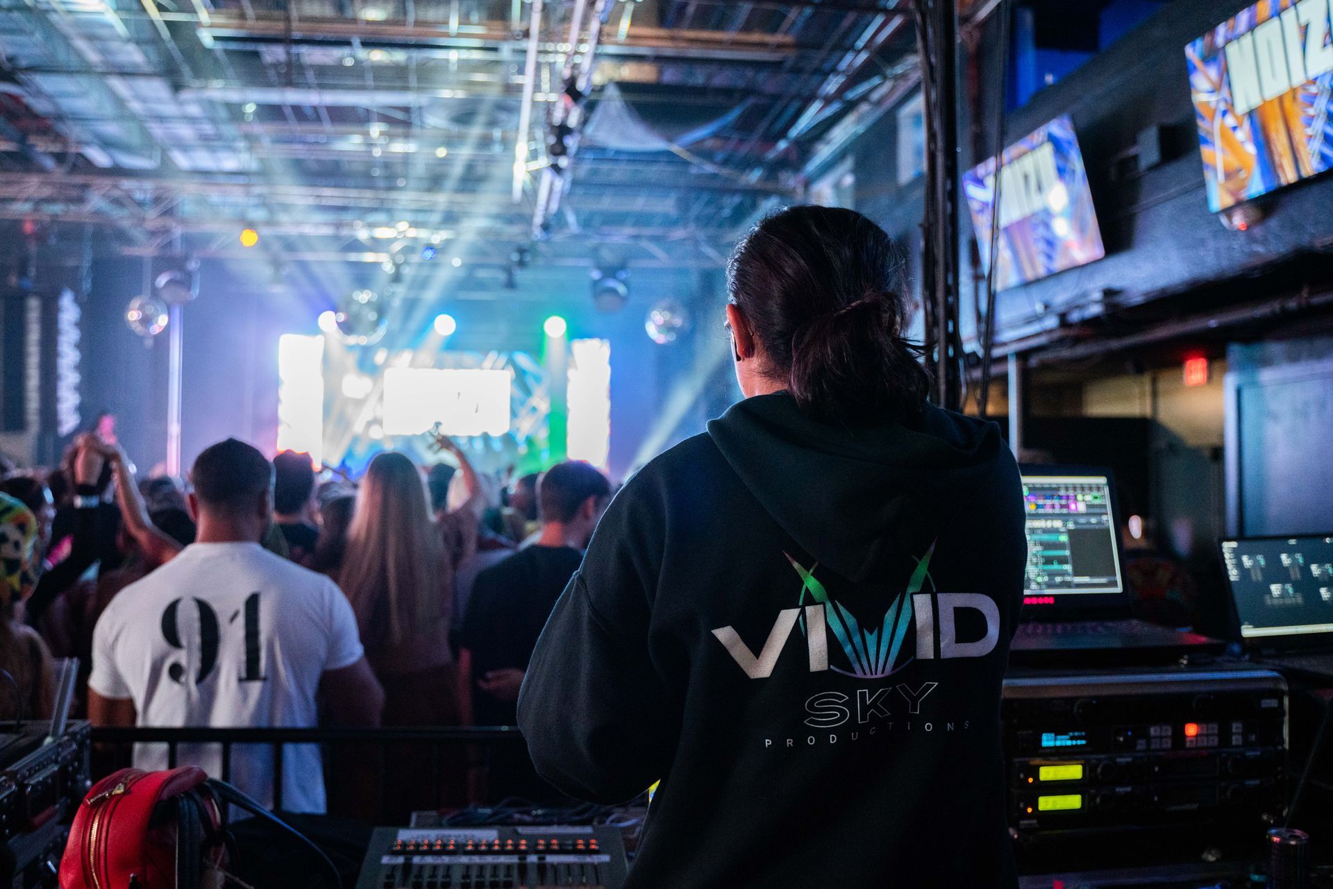 A man in a black hoodie is standing in front of a crowd at a concert.