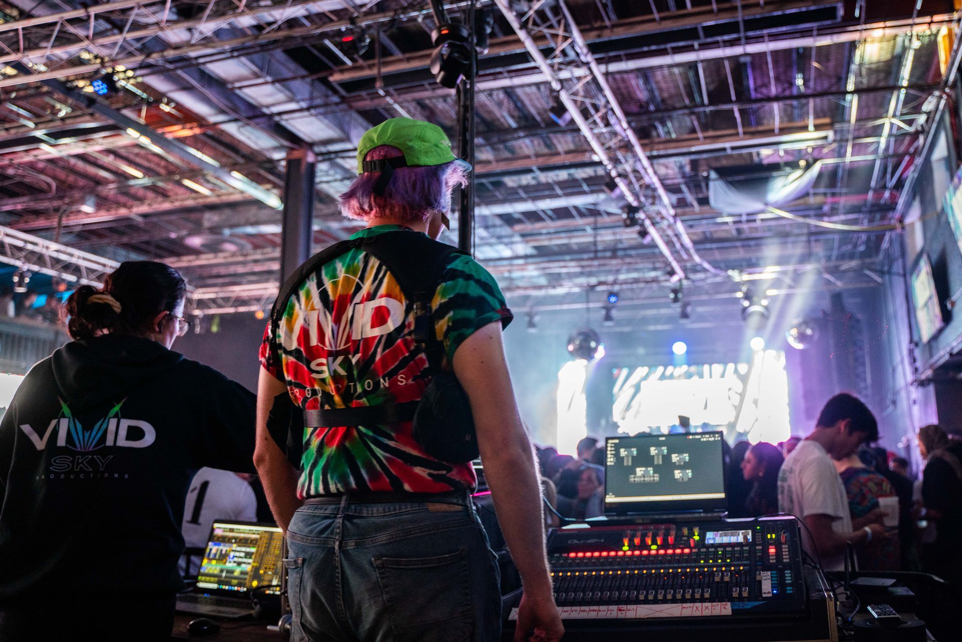 A woman in a tie dye shirt is standing in front of a crowd at a concert.
