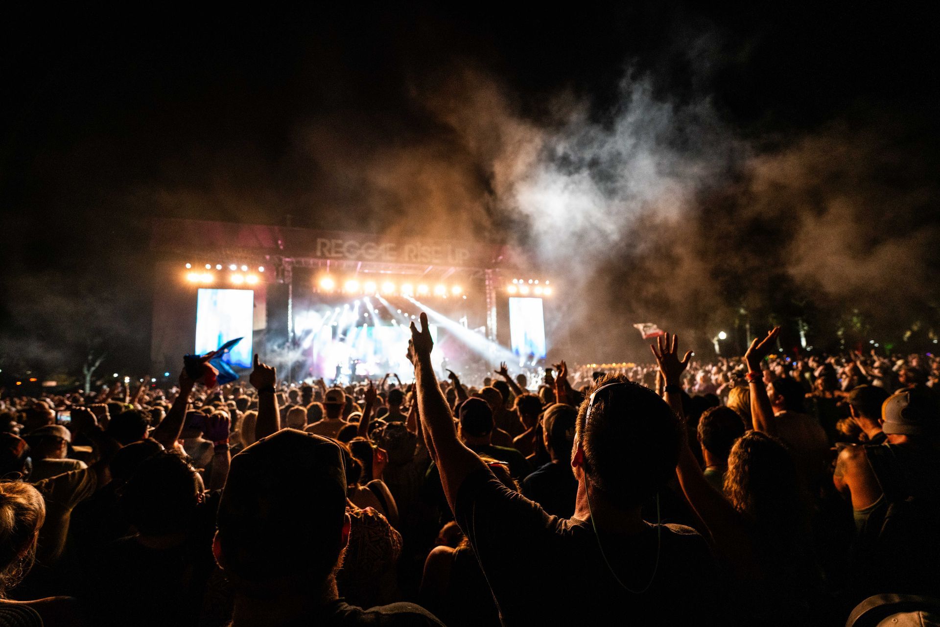 A crowd of people are standing in front of a stage at a concert.