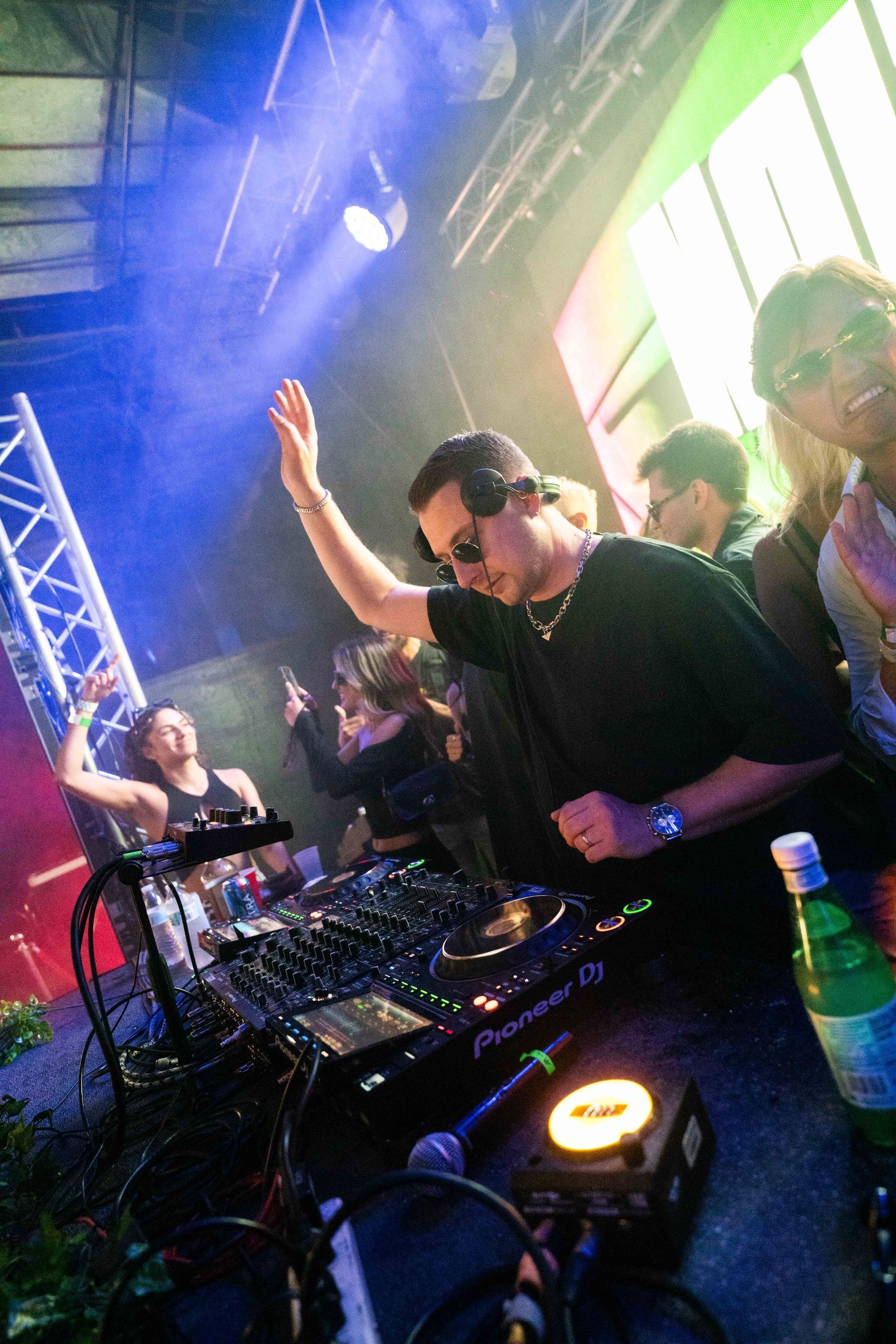 A man is standing in front of a dj mixer in a club.
