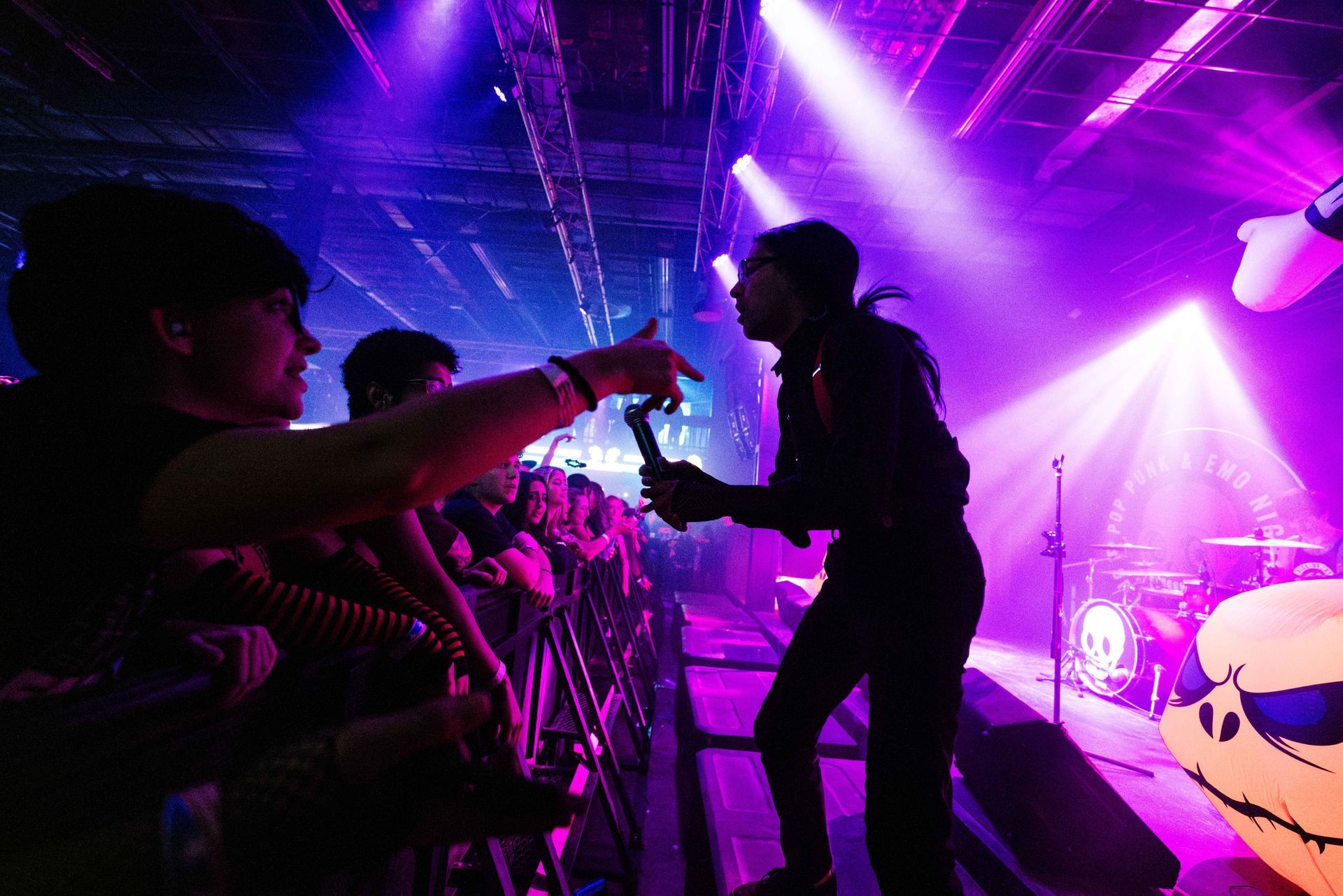 A man is standing on a stage holding a microphone in front of a crowd of people.