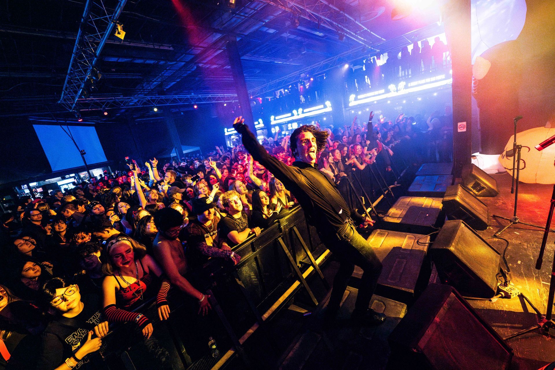 A man is jumping in the air in front of a crowd at a concert.