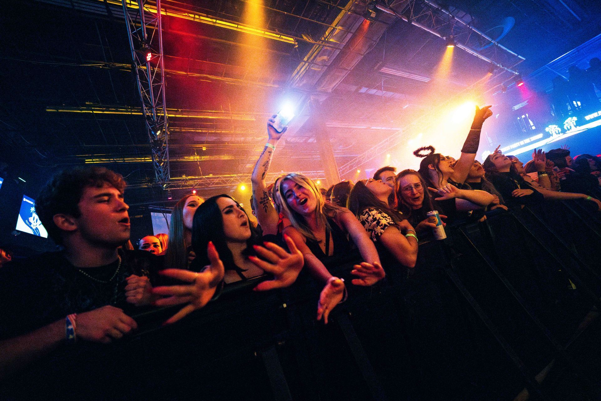 A crowd of people are standing in front of a stage at a concert.