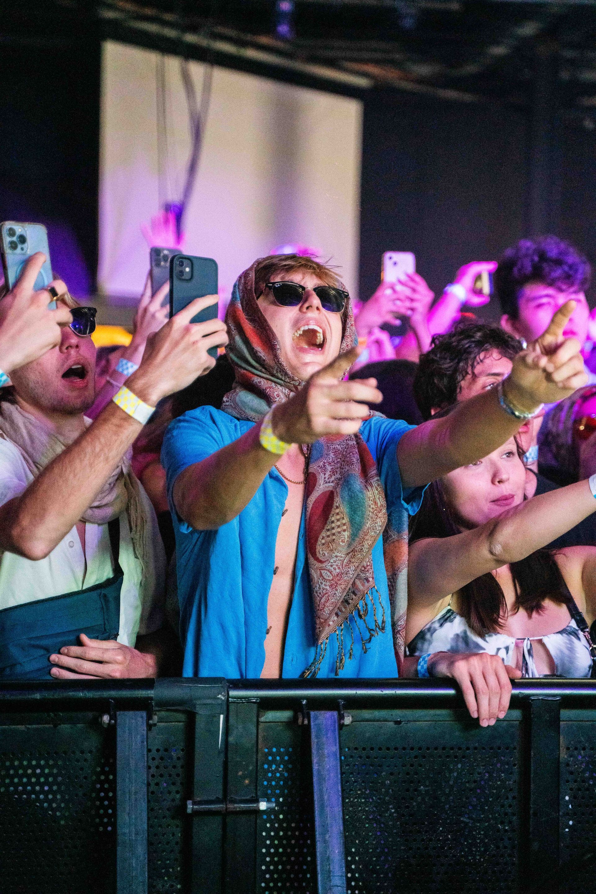 A crowd of people are taking selfies at a concert.