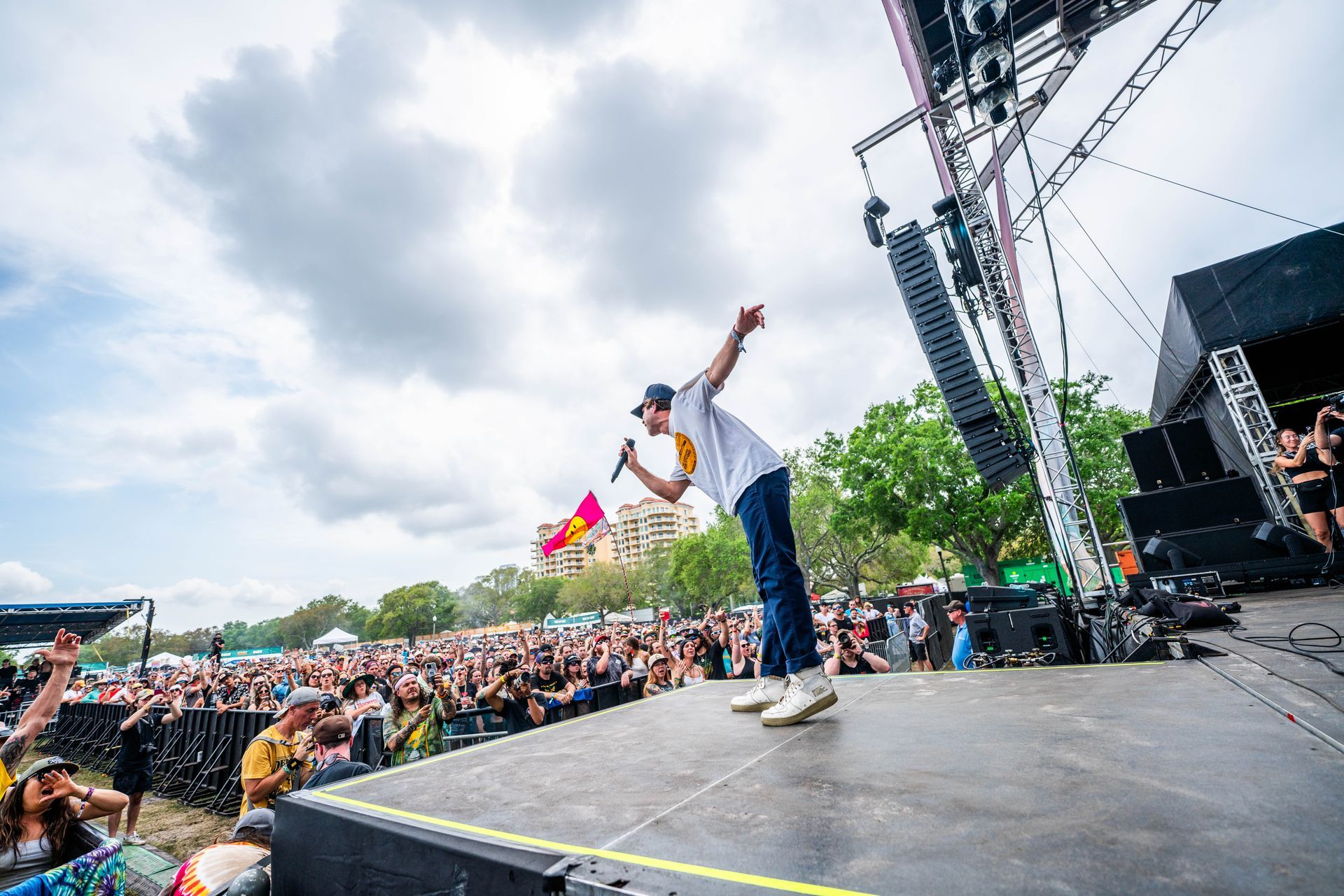 A man is standing on a stage holding a microphone in front of a crowd.