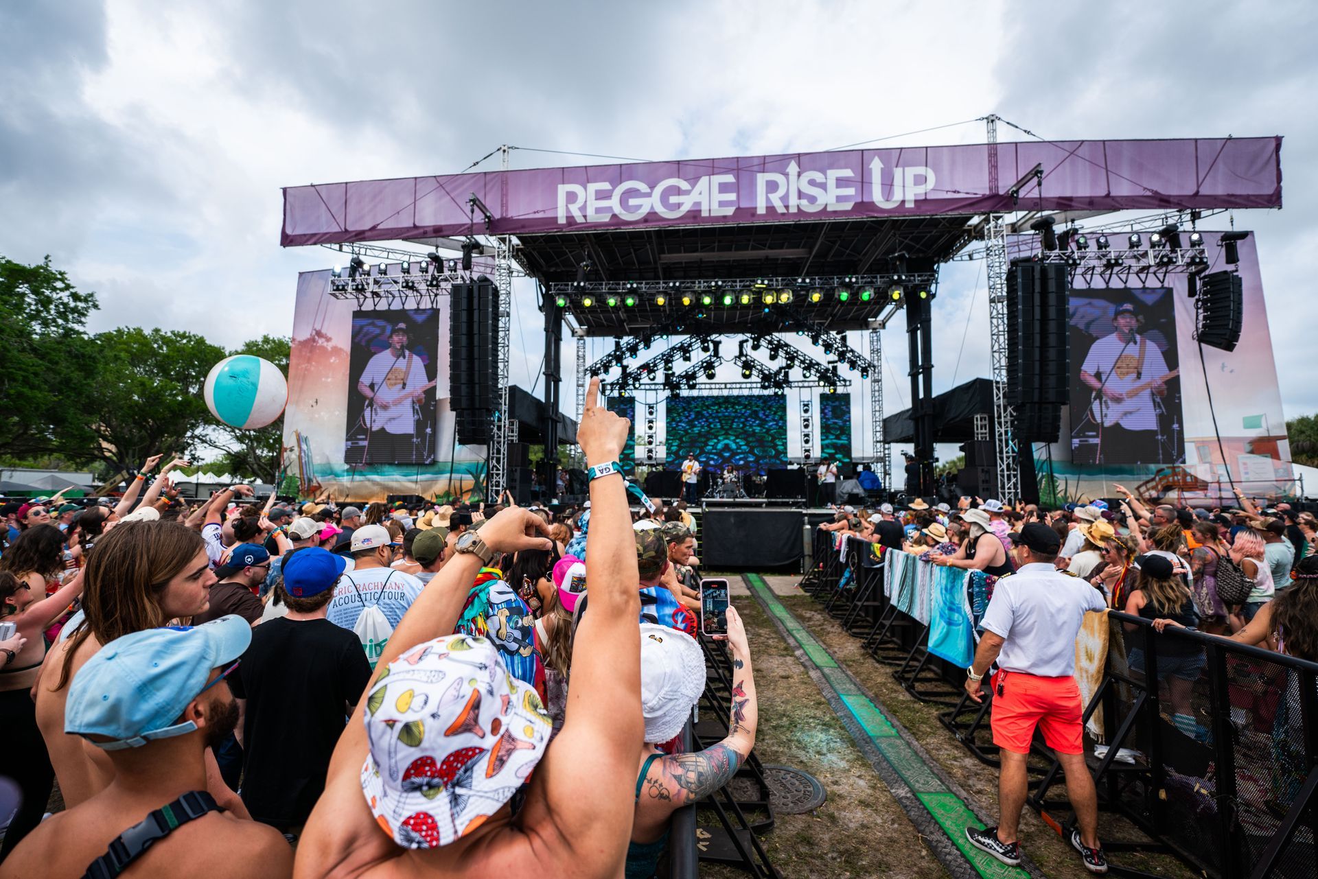 A crowd of people are standing in front of a stage at a music festival.