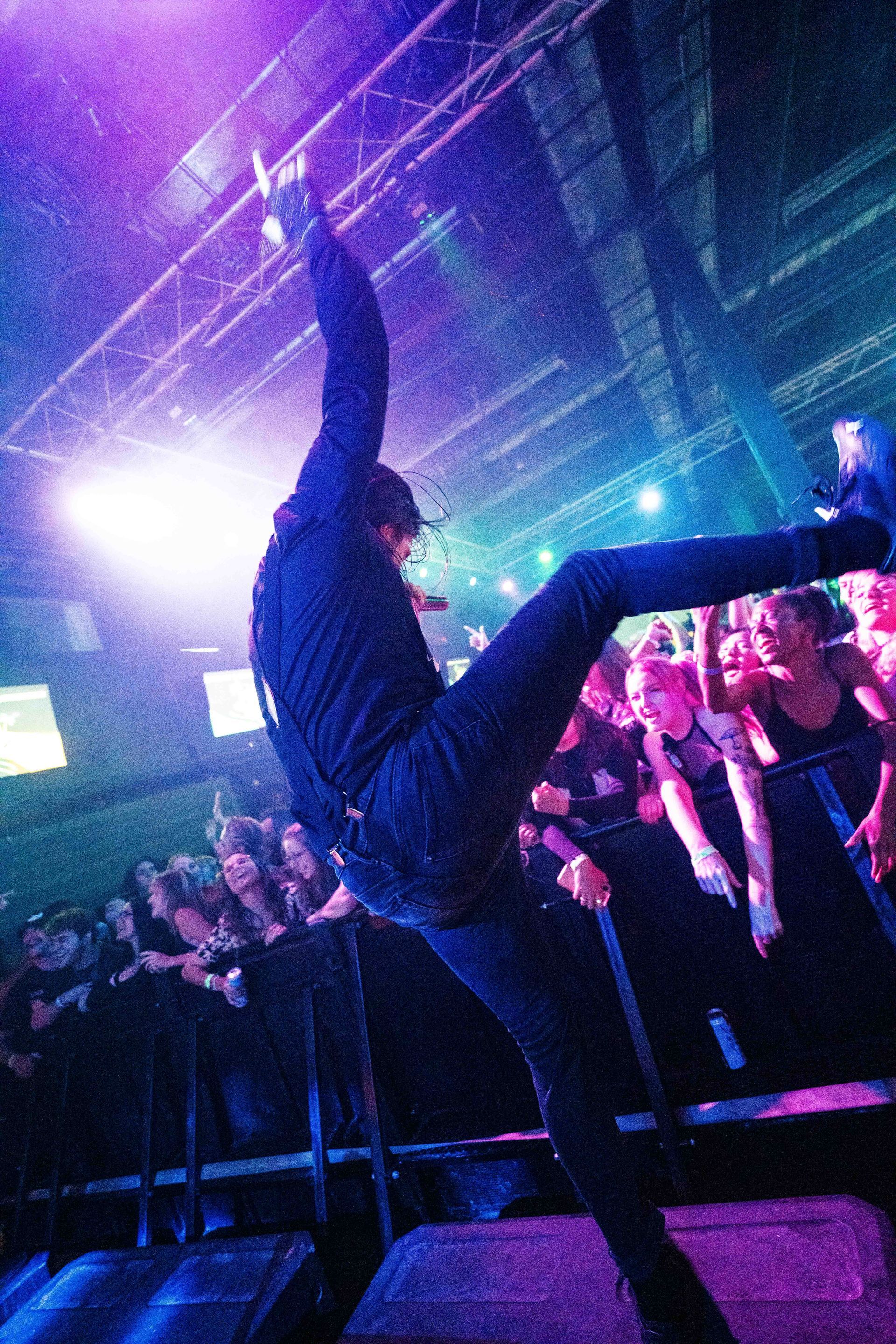 A man is flying through the air on a stage in front of a crowd.