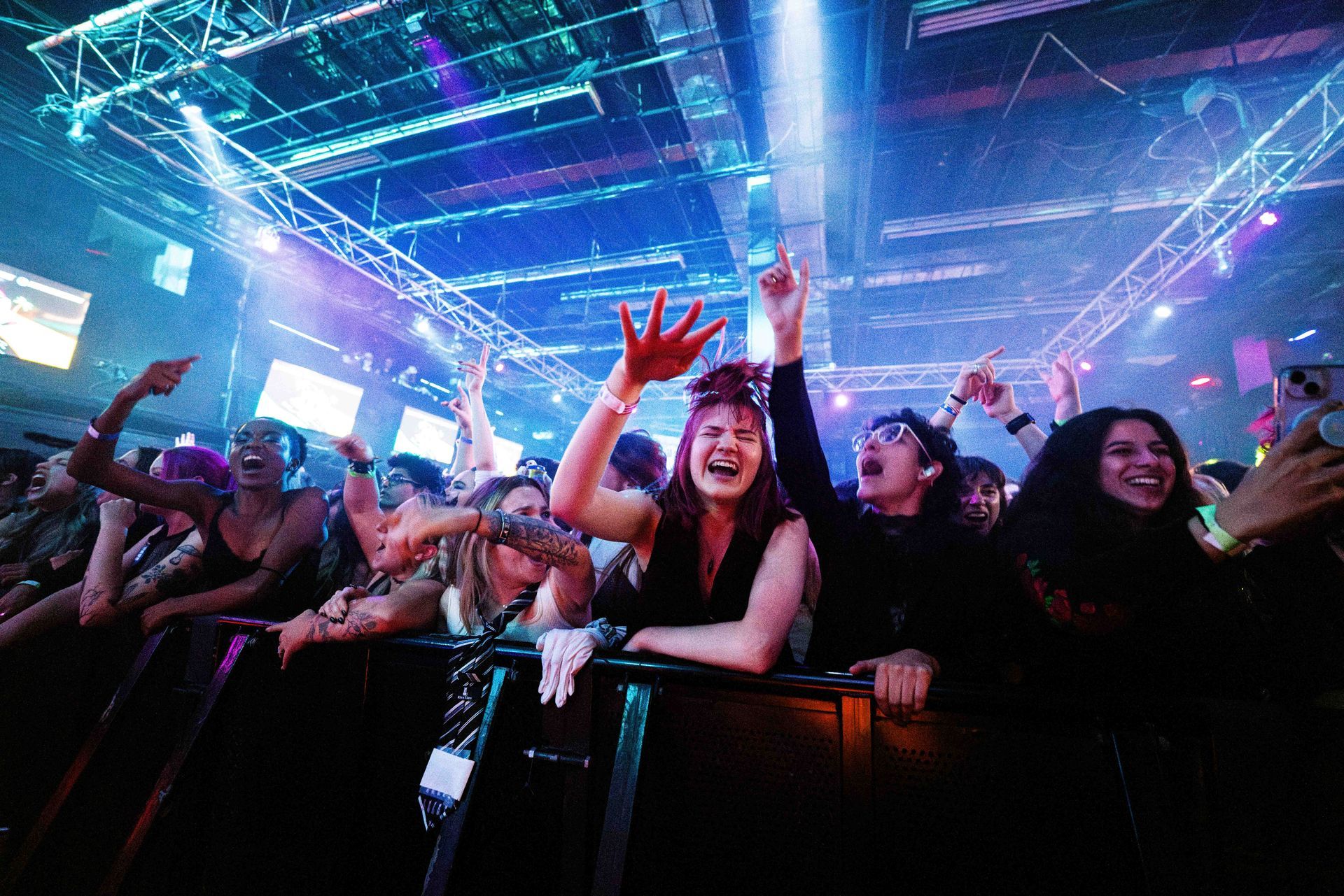 A crowd of people are standing in a dark room at a concert.