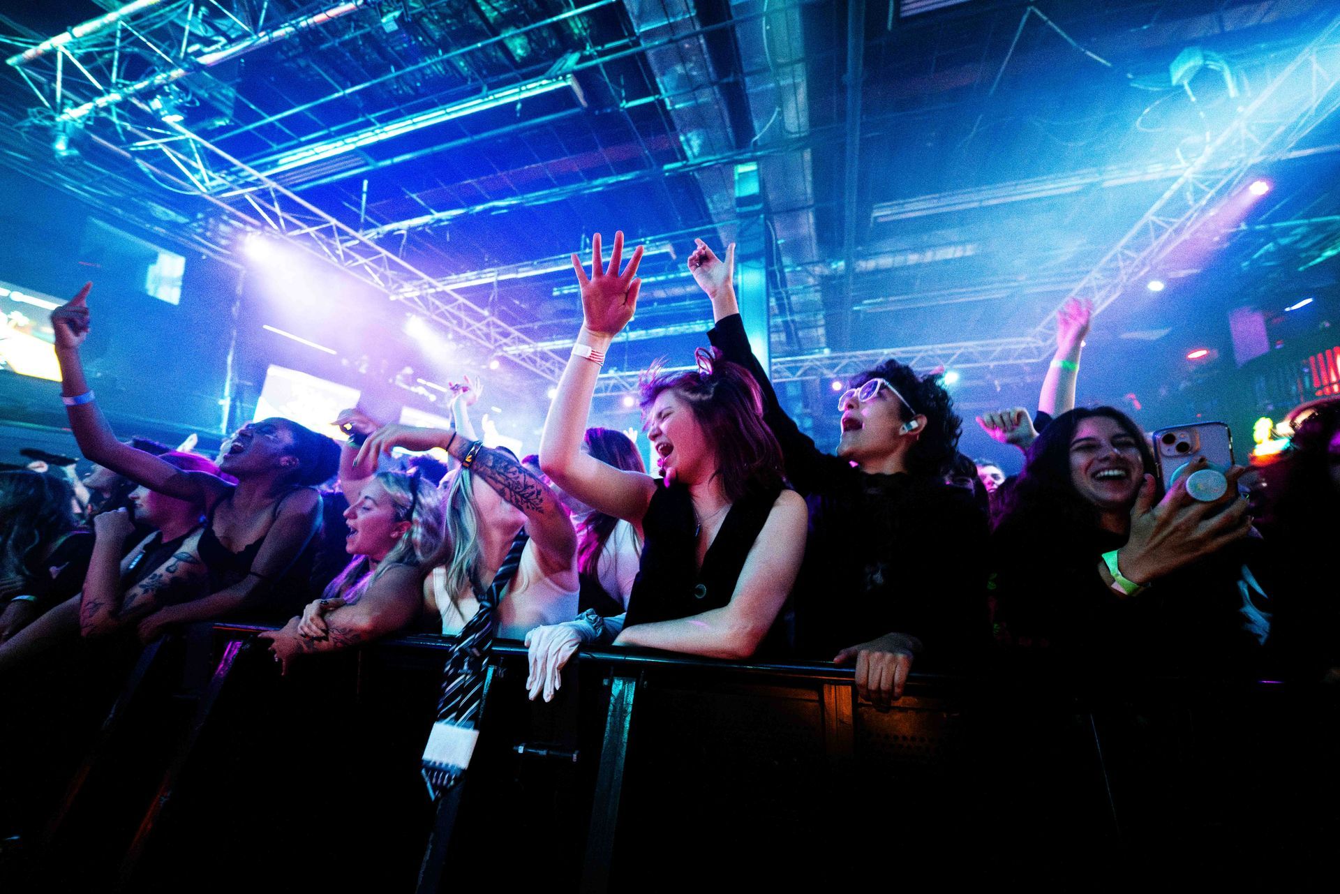 A crowd of people at a concert with their hands in the air.