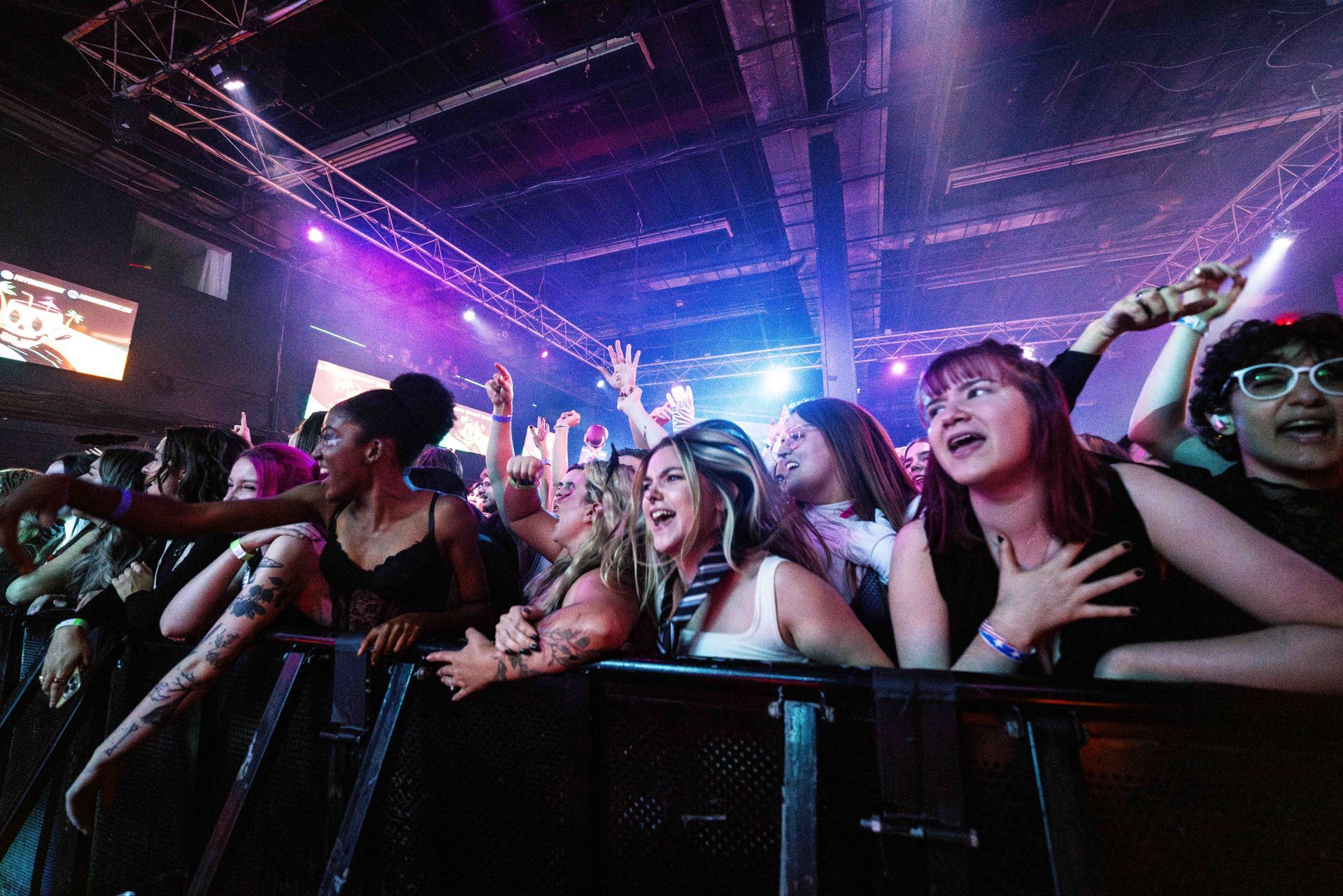 A crowd of people are standing in a dark room at a concert.