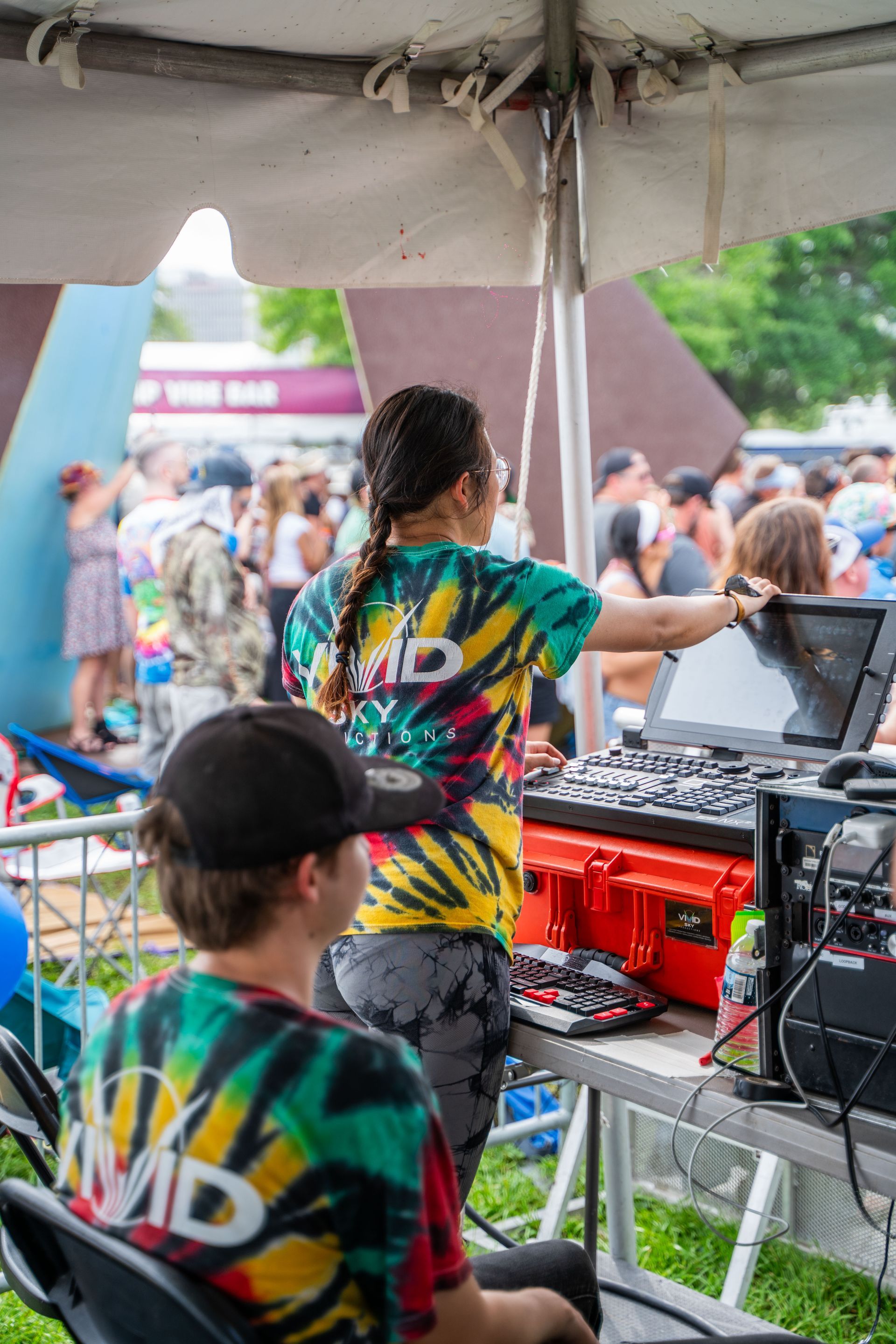 A woman is standing in front of a dj booth at a festival.