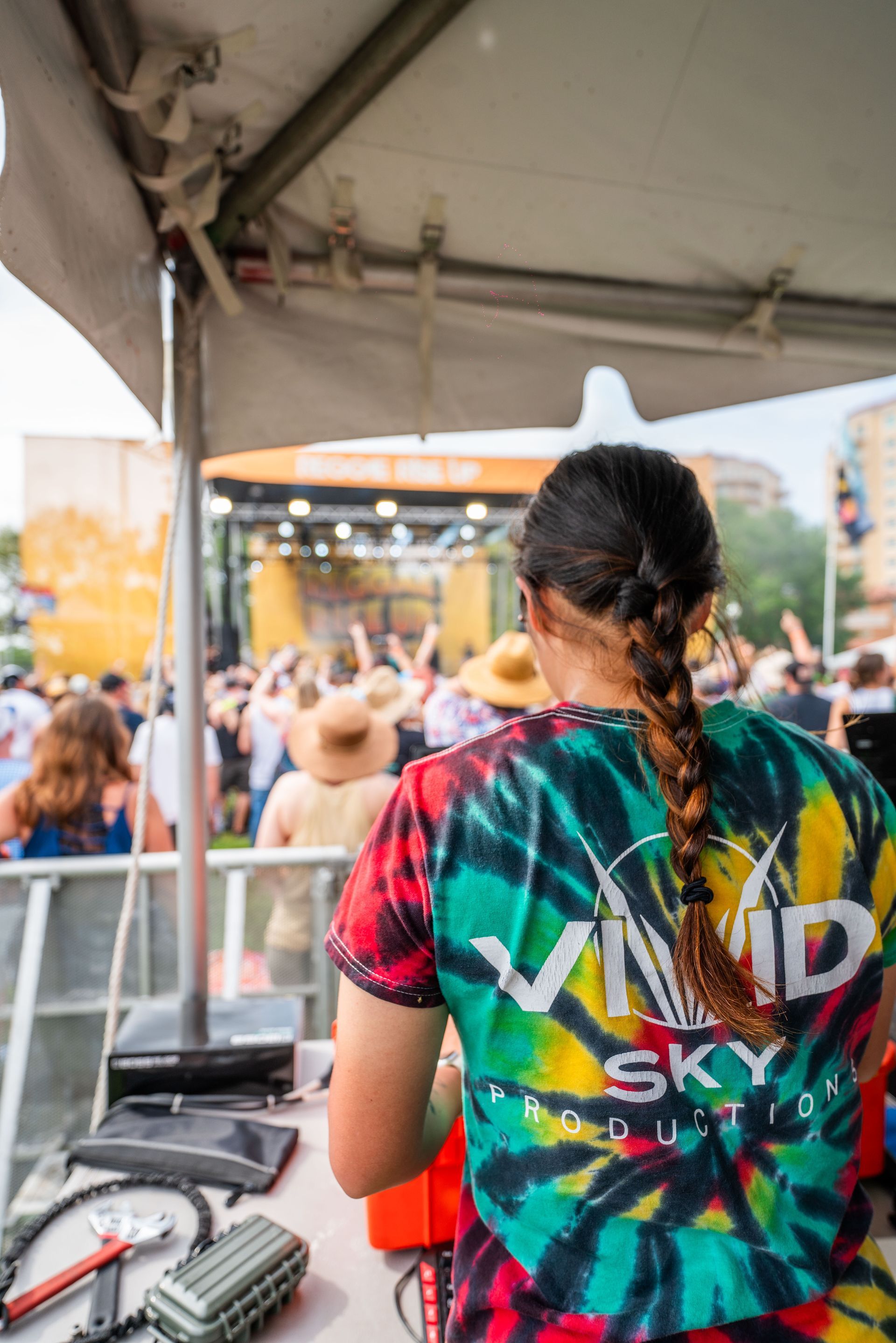 A woman in a tie dye shirt is standing in front of a crowd at a concert.