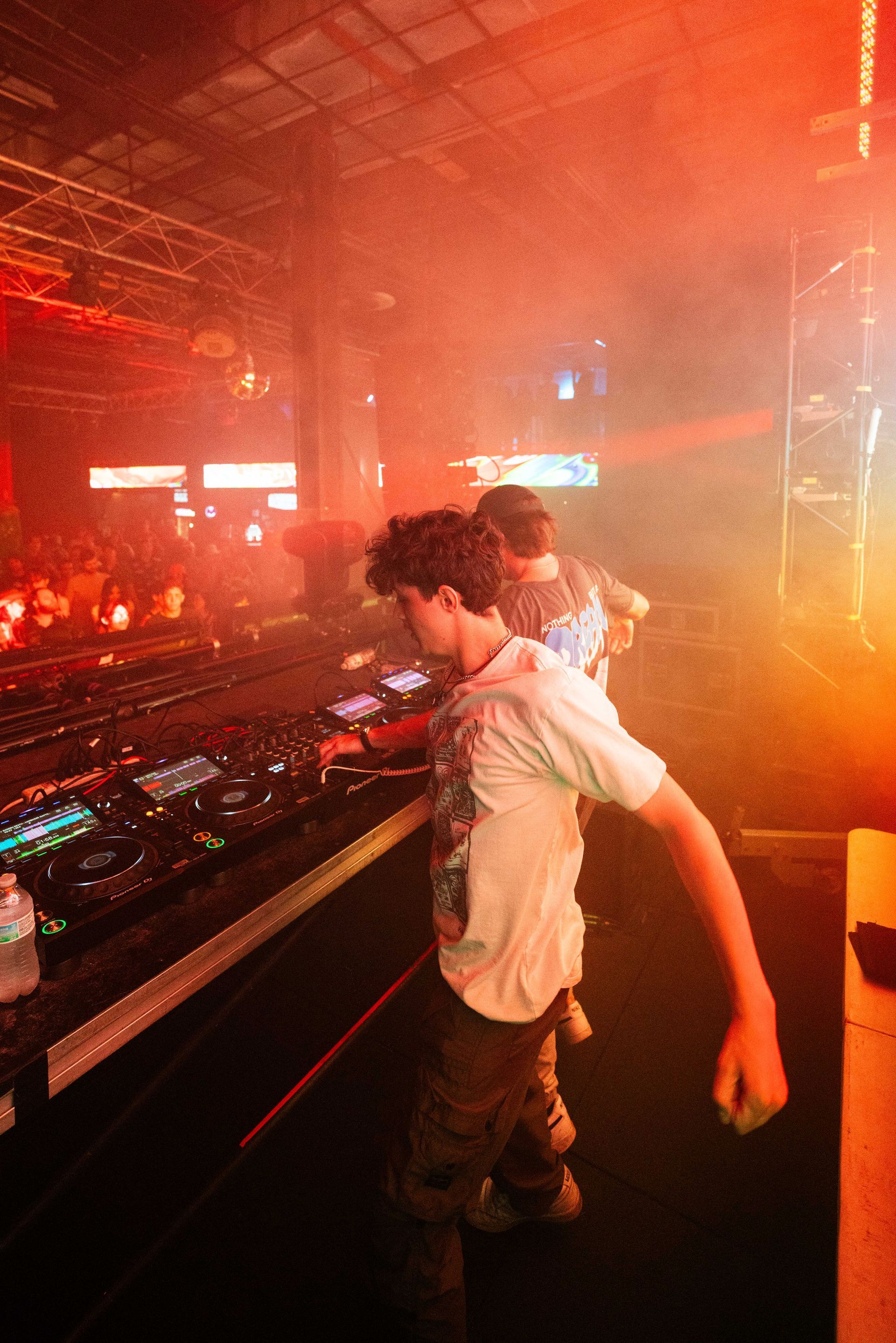A man is playing a dj set in a dark room.