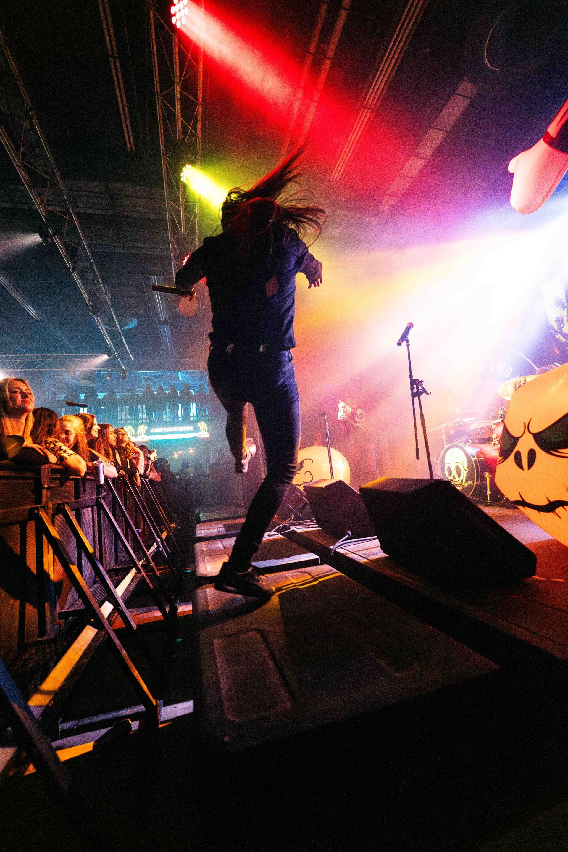 A person is jumping in the air on a stage in front of a crowd
