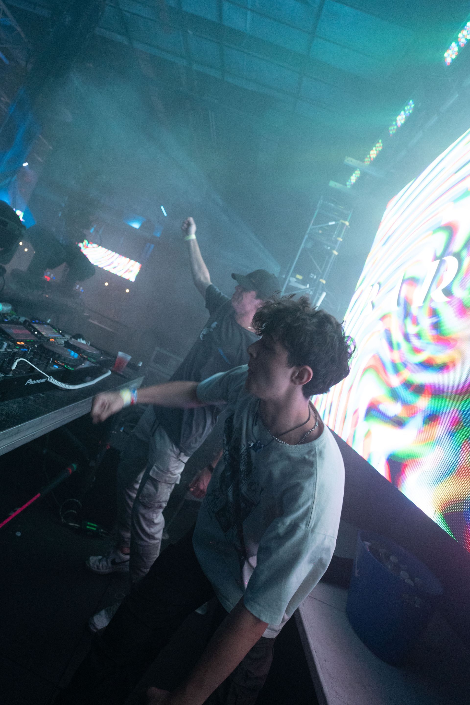 A man is standing in front of a dj booth at a concert.