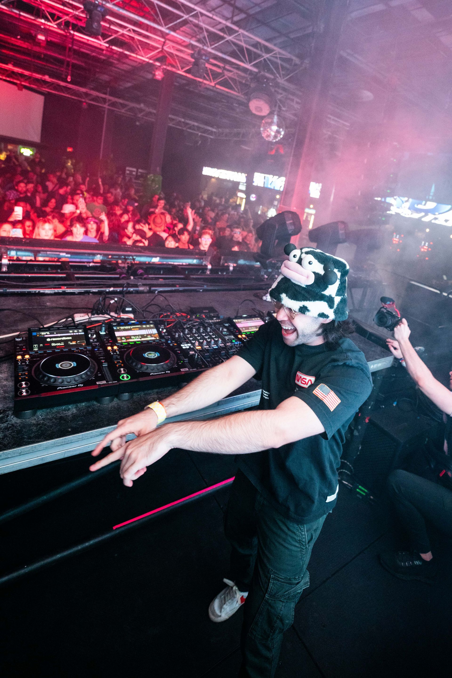 A man is standing in front of a dj booth in a club.