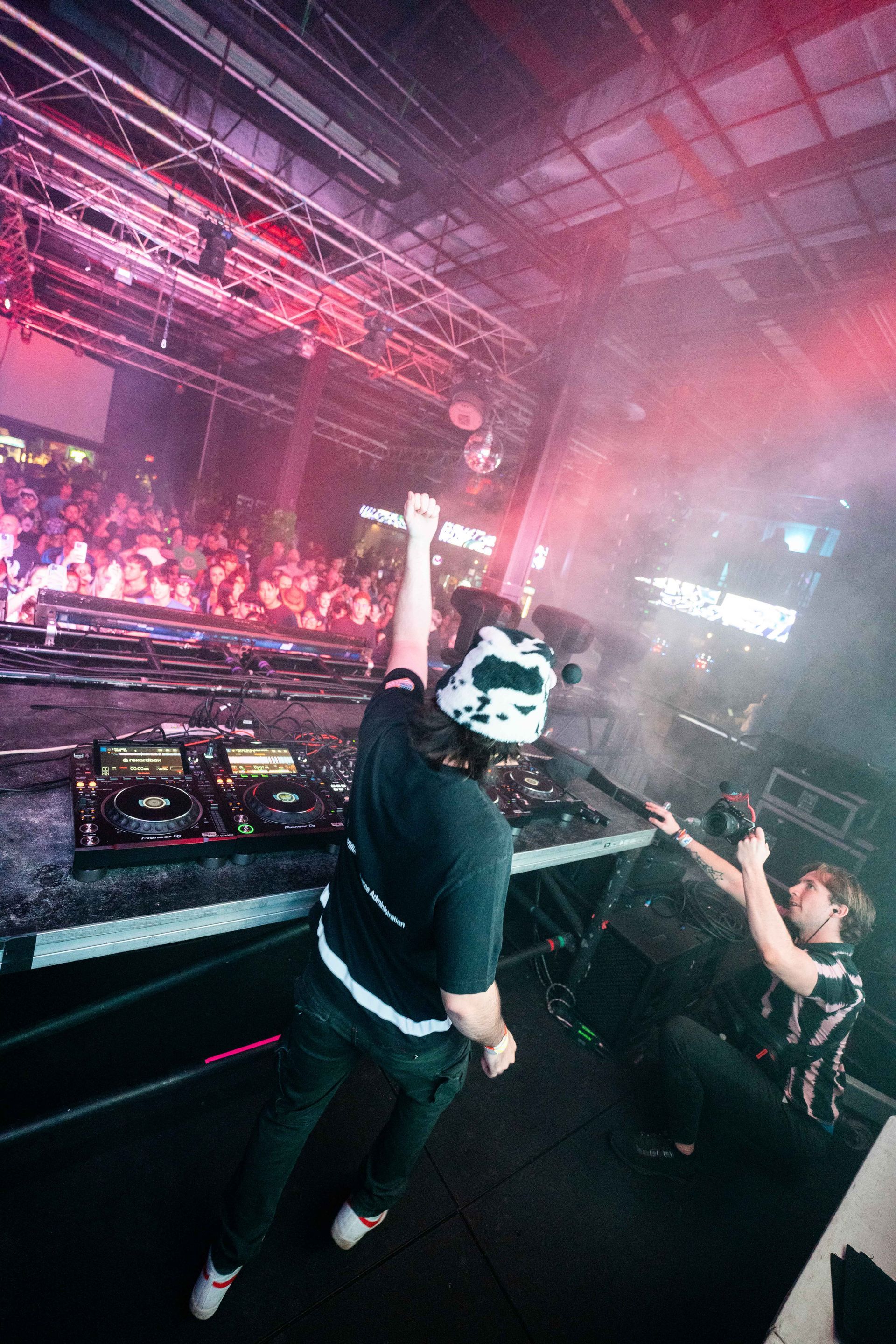 A man is playing a dj set in front of a crowd at a concert.