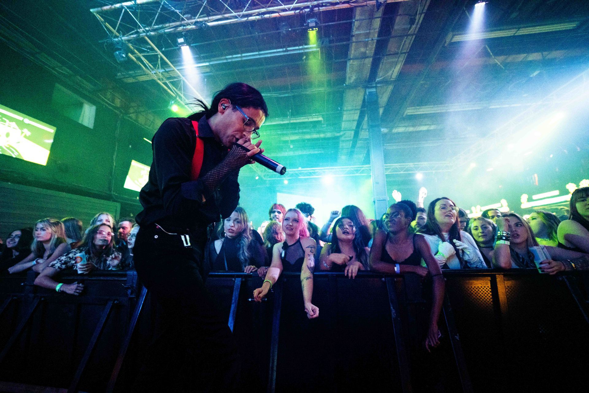 A man is singing into a microphone in front of a crowd at a concert.
