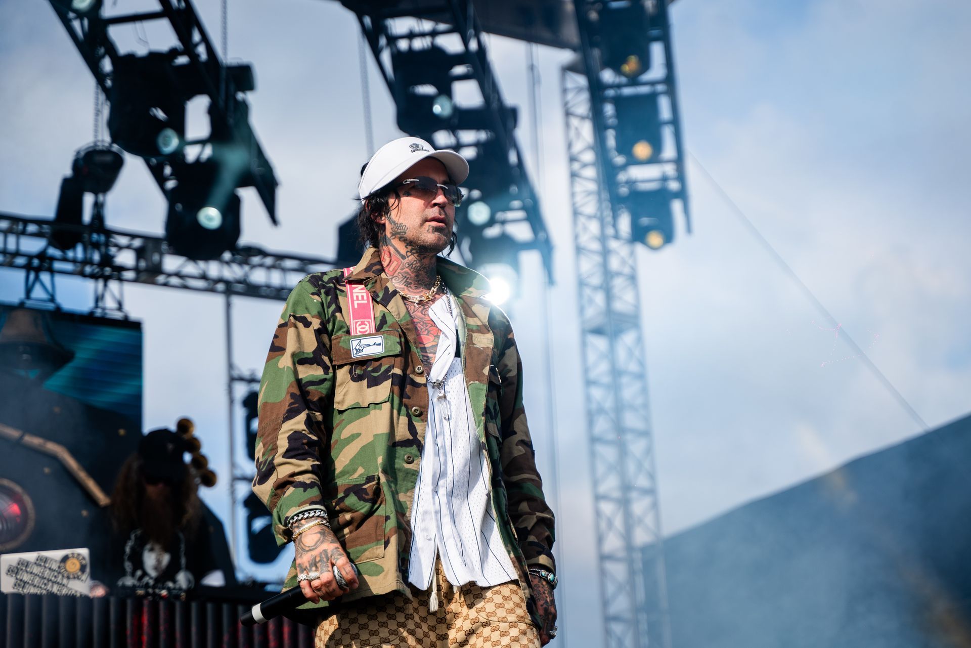 A man in a camouflage jacket and hat is standing on a stage.