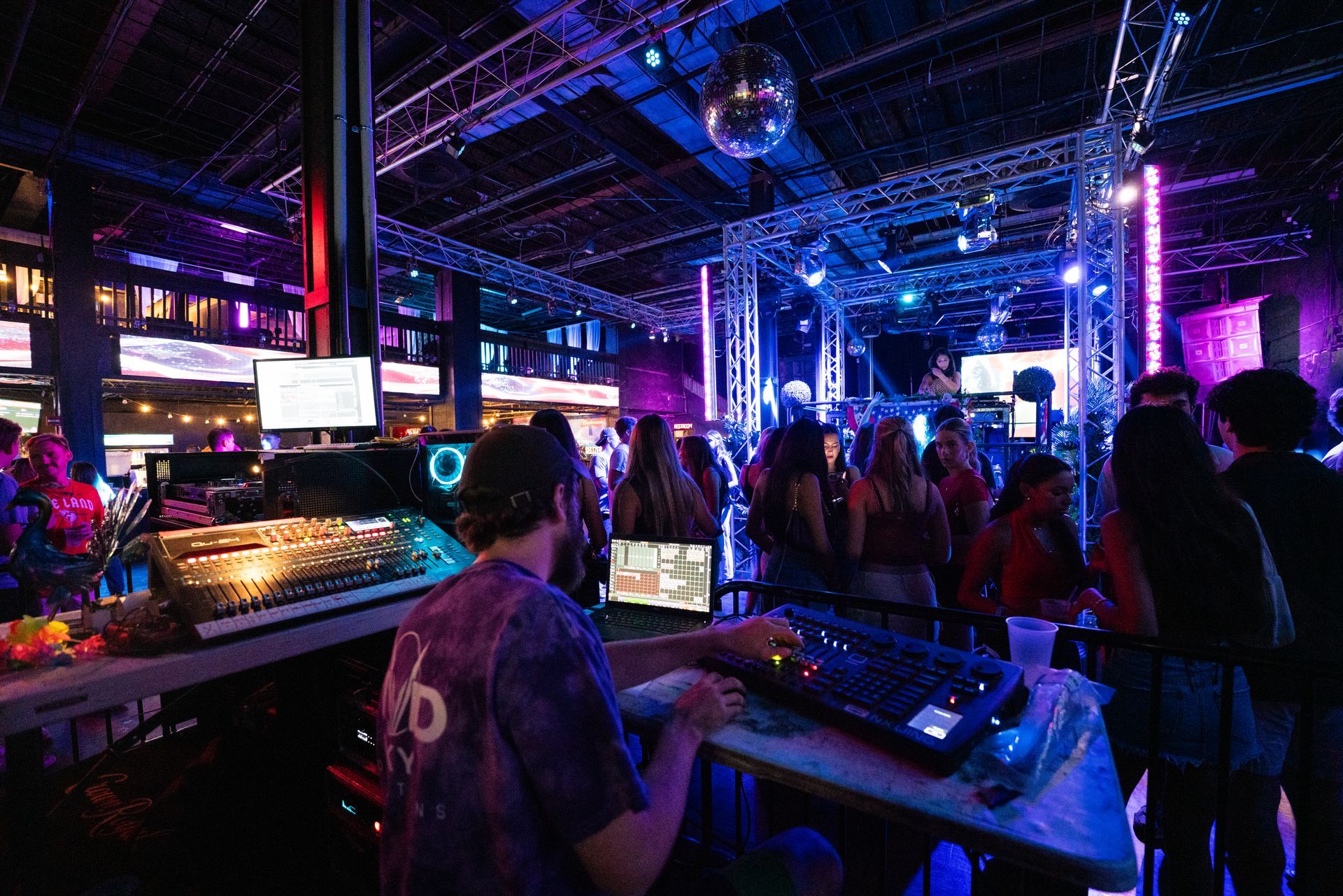 A dj is playing music at a party in a dark room.