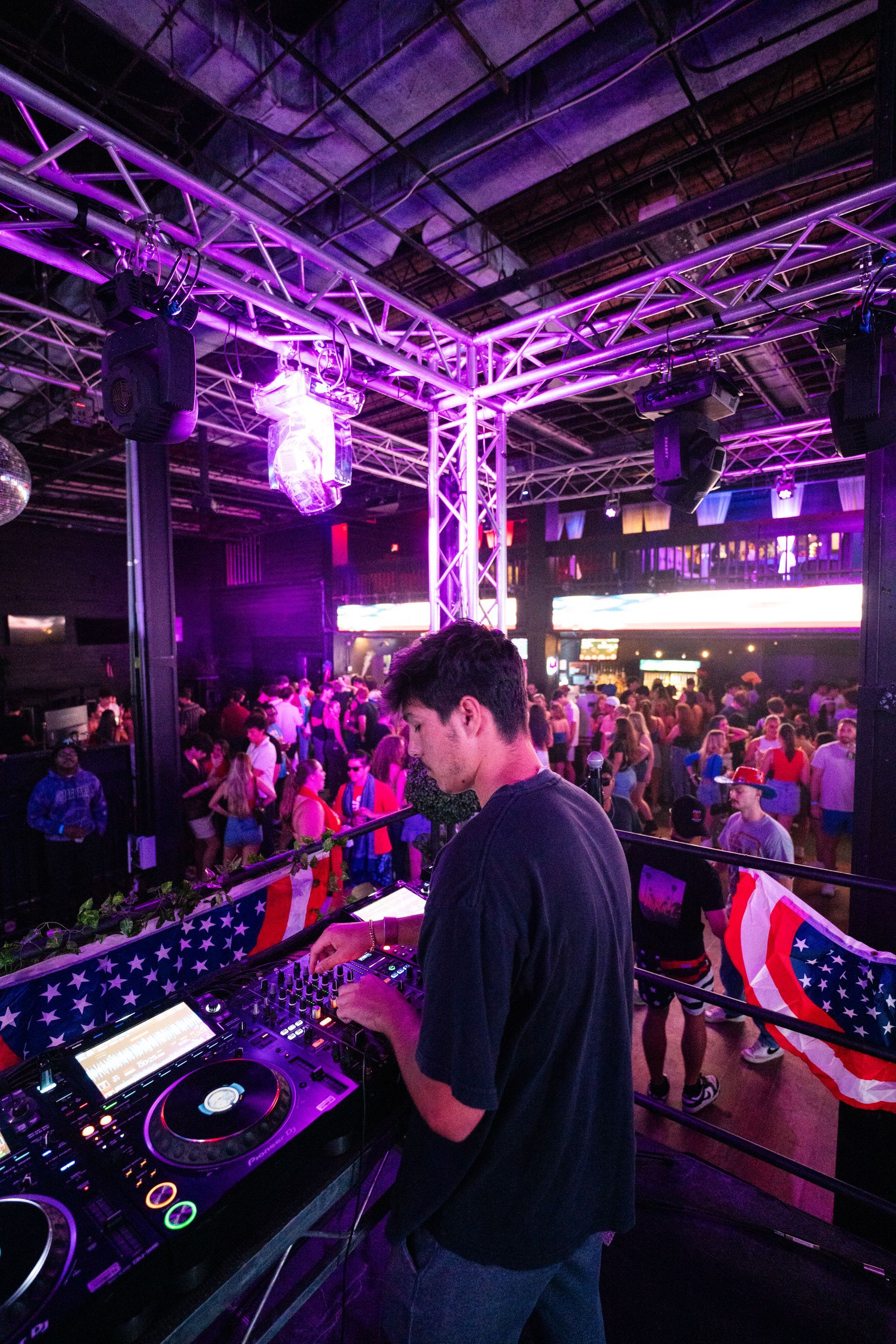 A man is standing in front of a dj booth at a party.