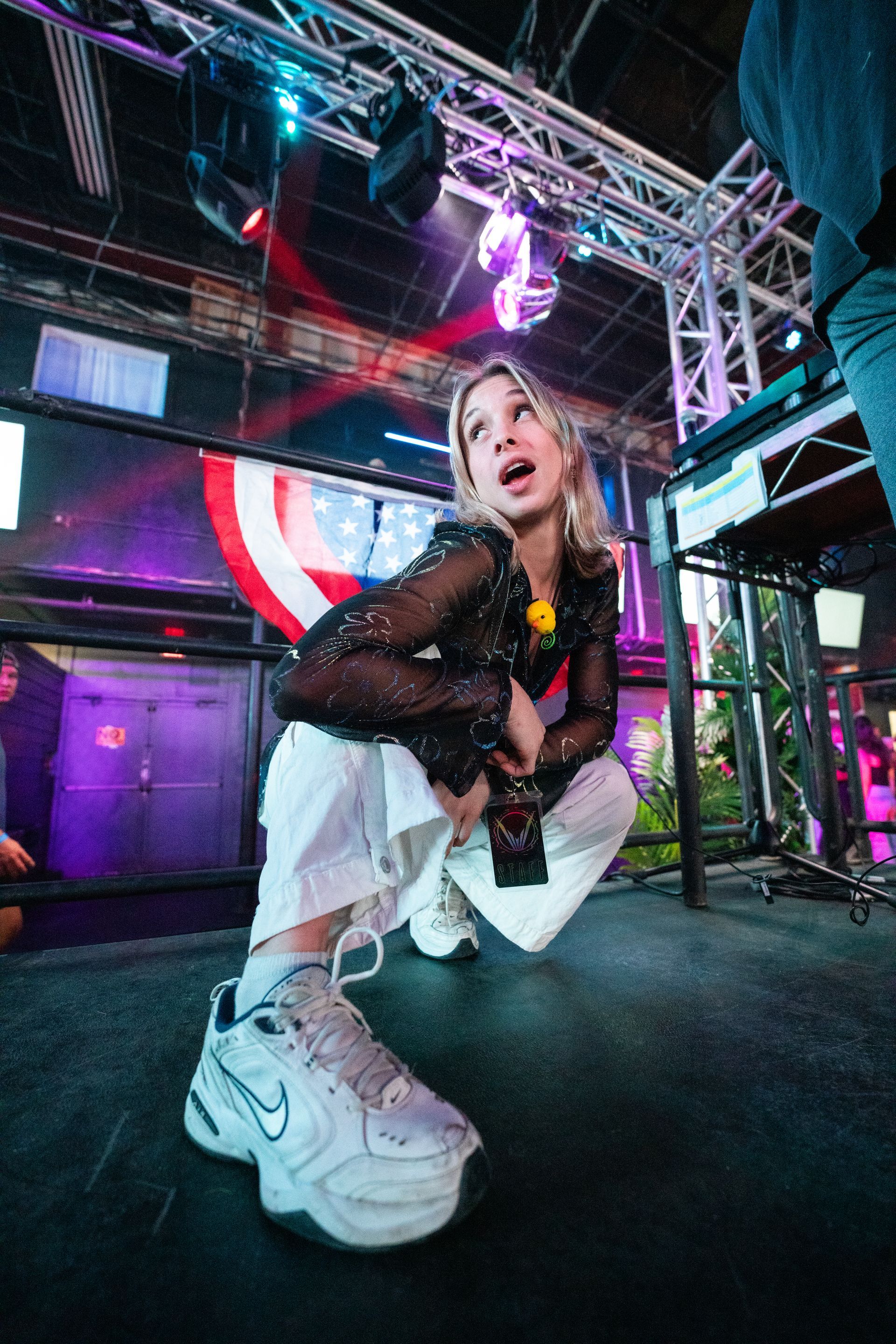A woman is kneeling on the floor in a club wearing nike shoes.