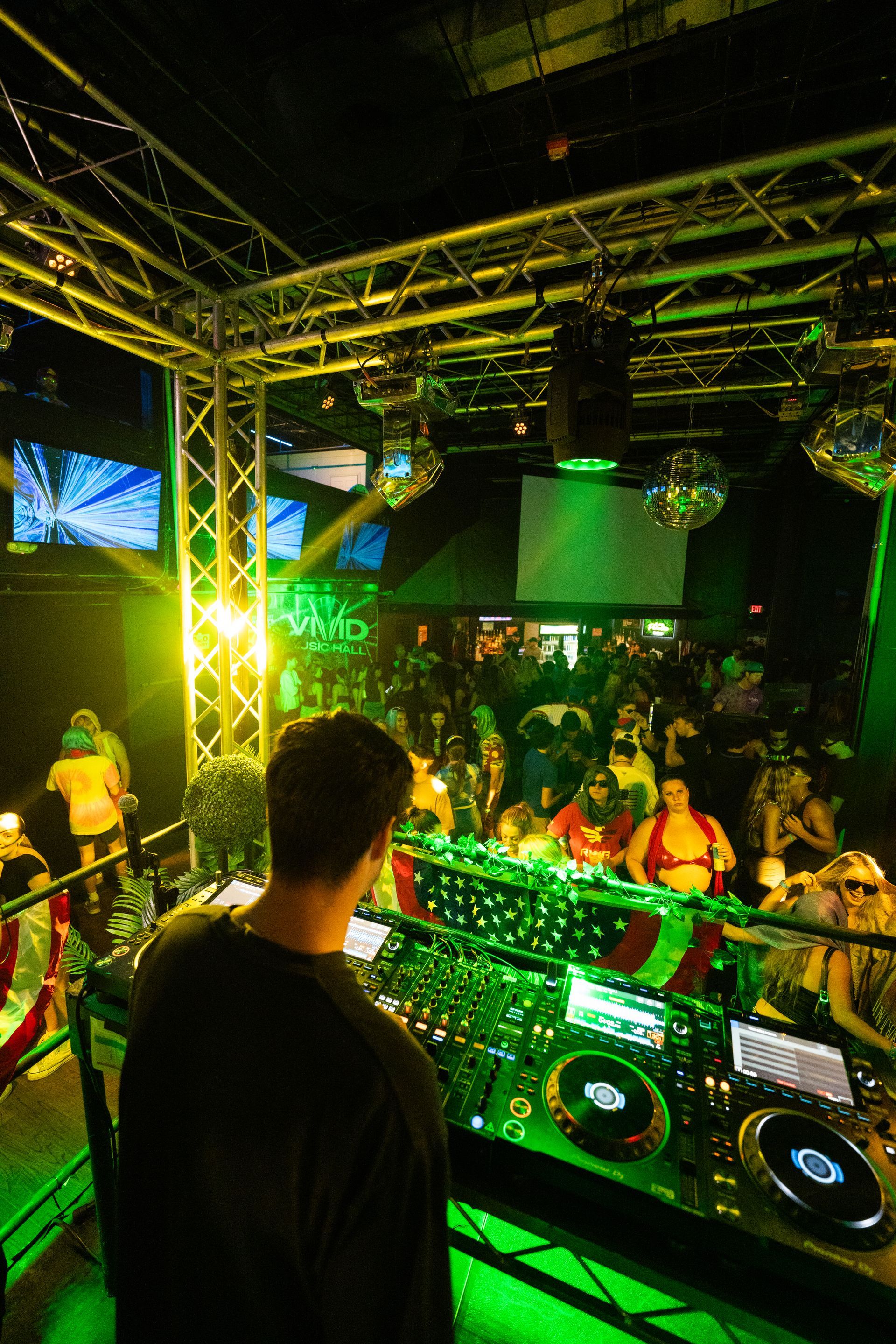 A man is standing in front of a dj booth at a party.