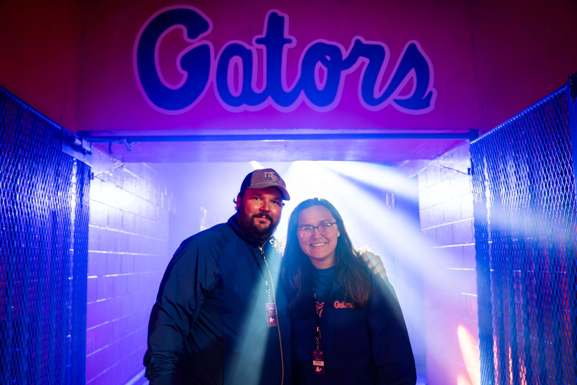 A man and a woman are standing in a tunnel under a sign that says gators.