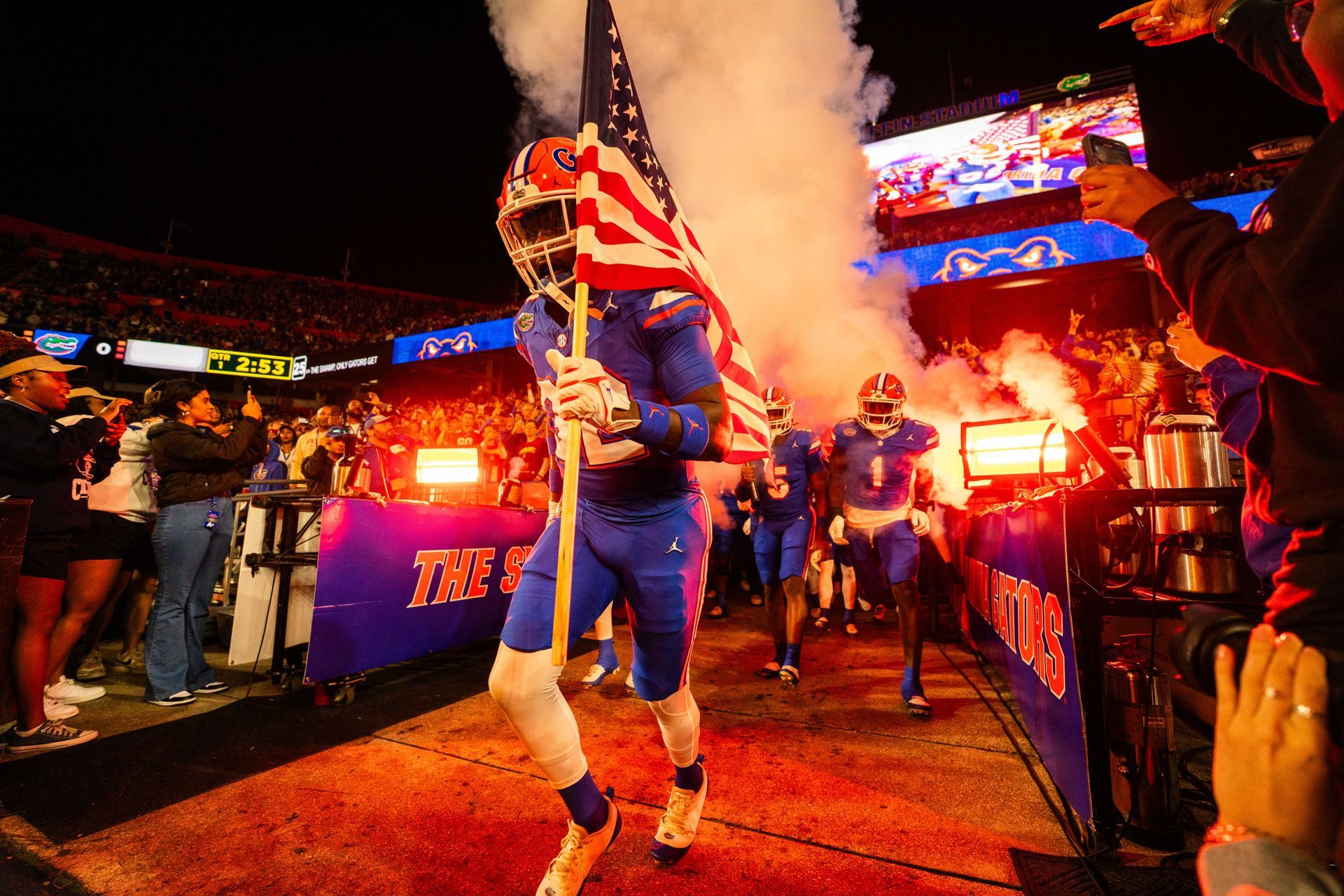 A football player is carrying an american flag on the field
