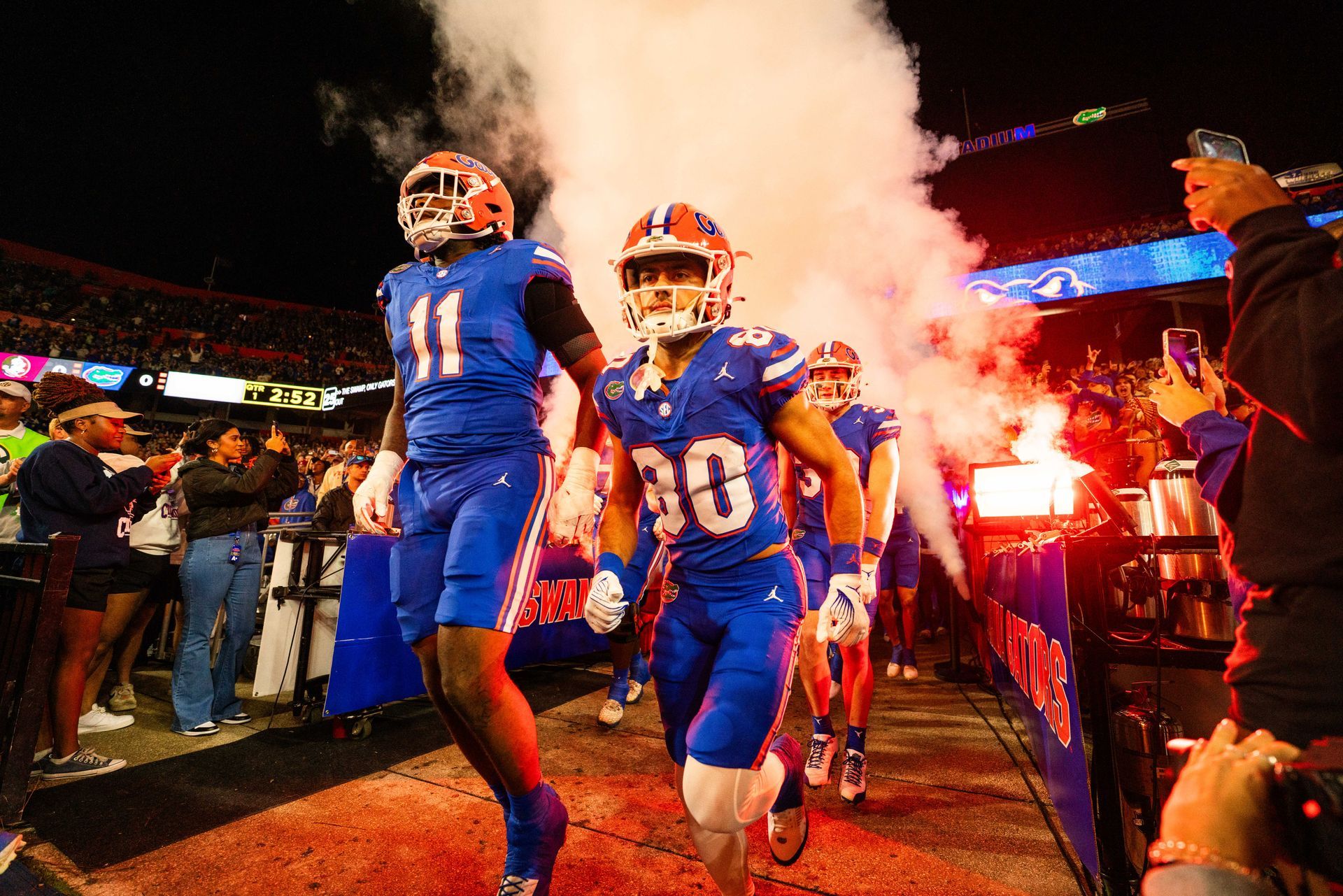 A group of football players are walking out of the tunnel on a field.