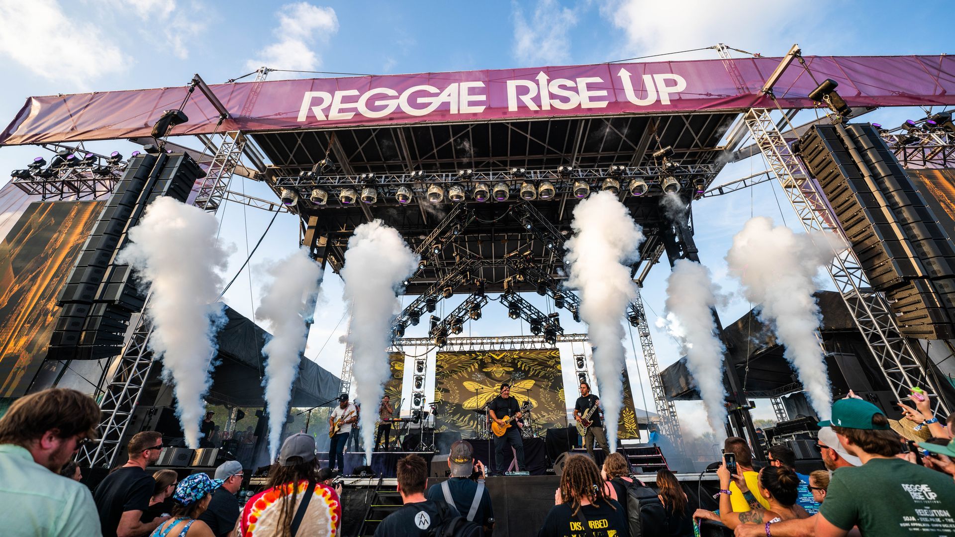 A group of people are standing in front of a stage with smoke coming out of it.