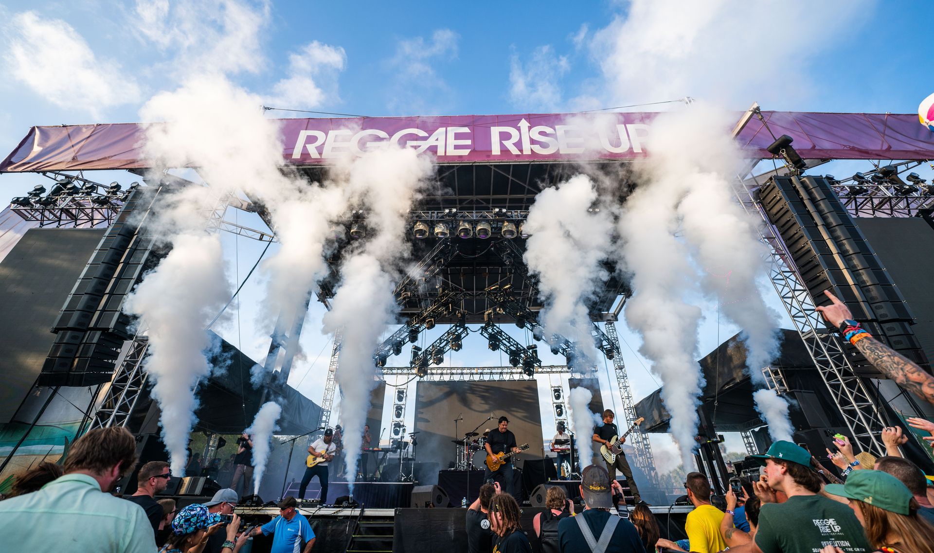 A group of people are standing in front of a stage with smoke coming out of it.