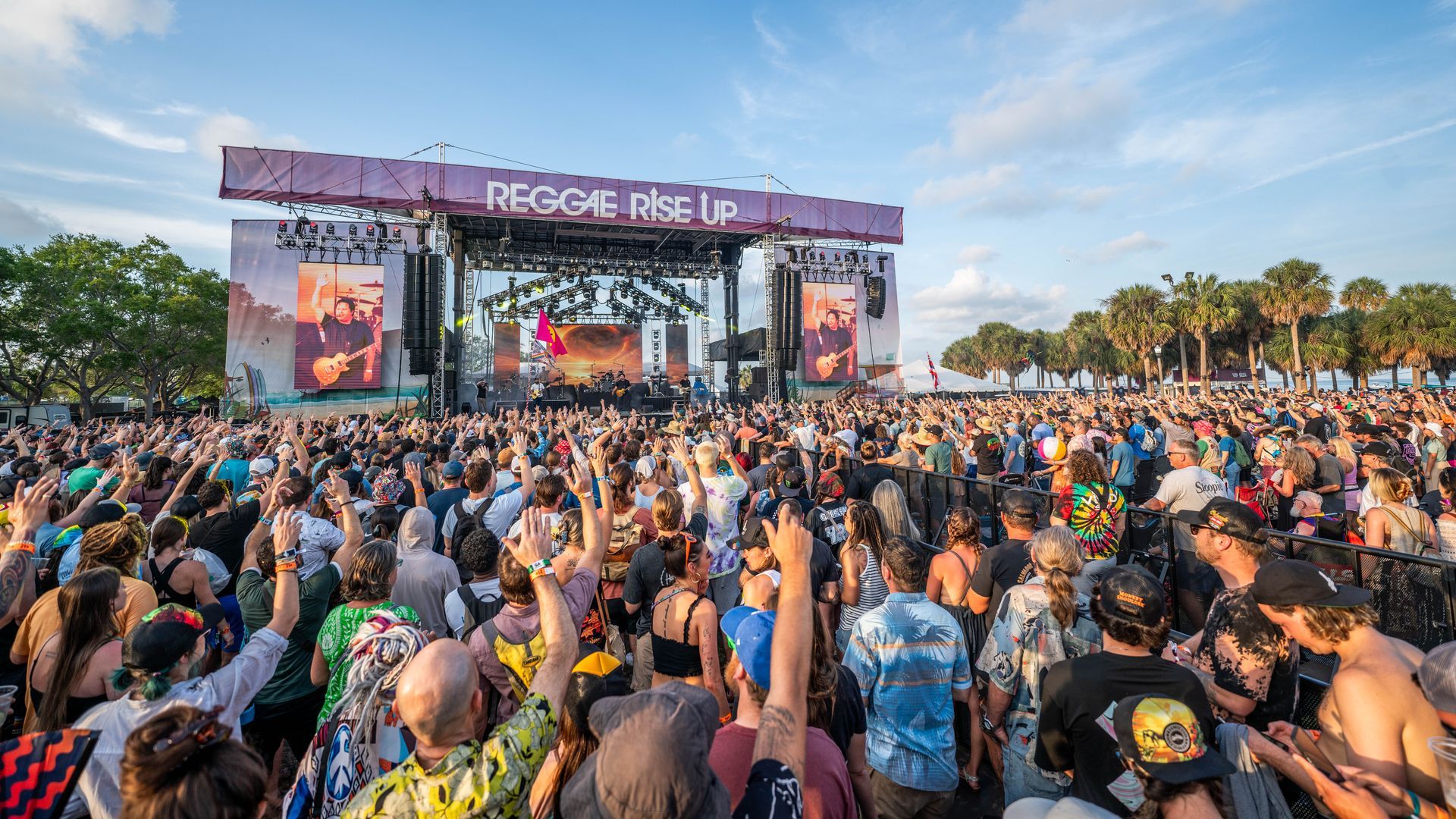A large crowd of people are standing in front of a stage at a music festival.