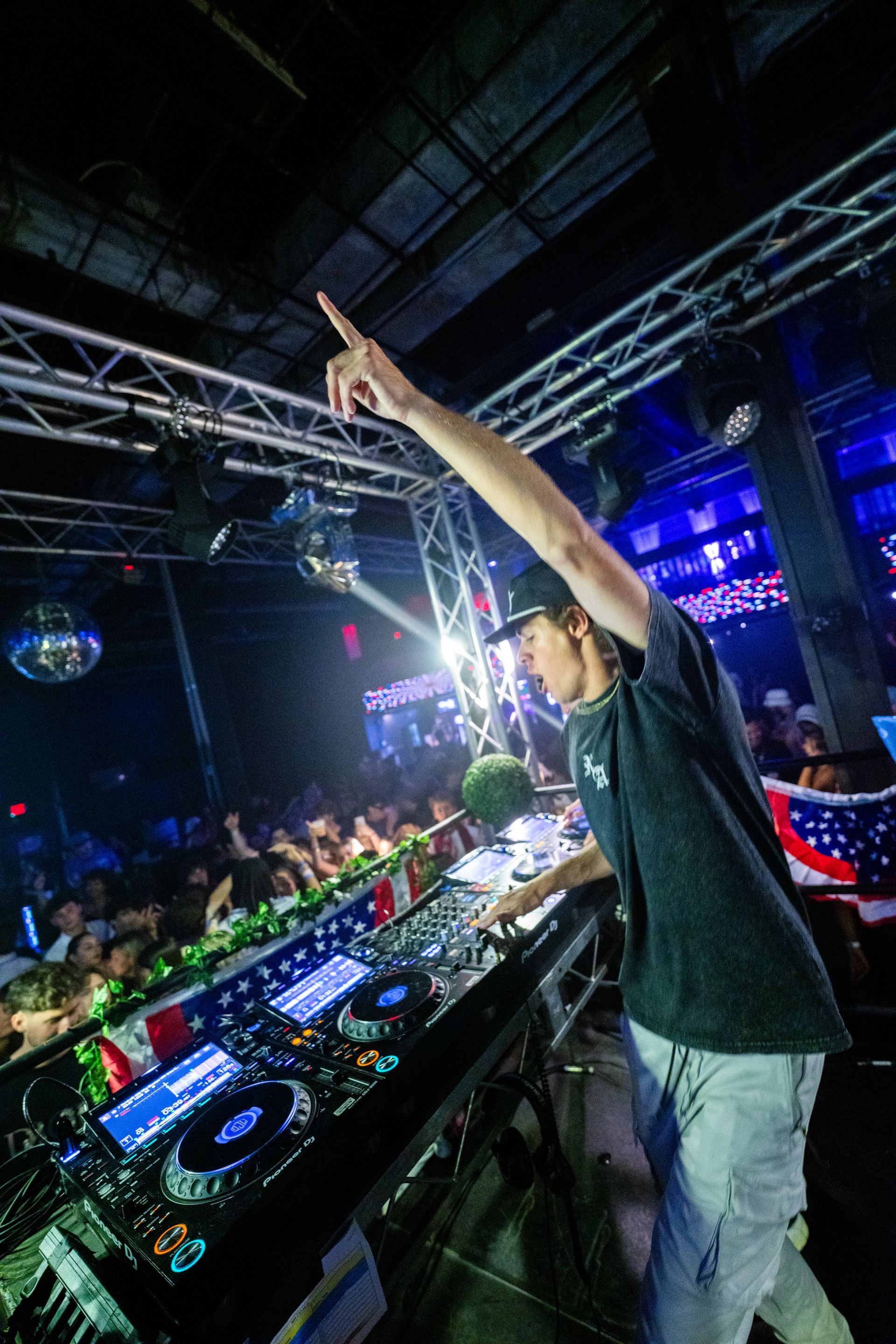 A man is playing a dj set in front of a crowd at a club.