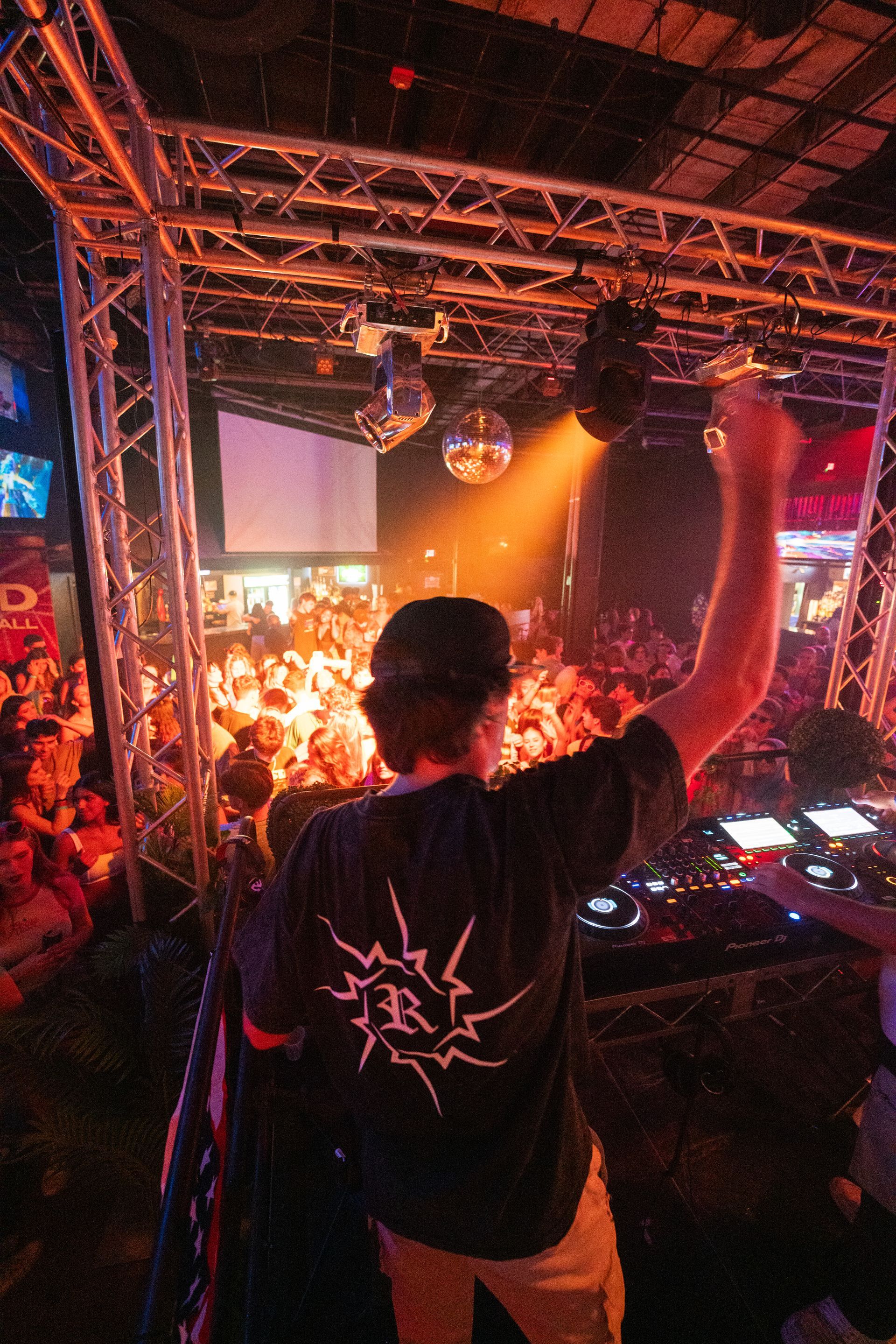 A man in a black shirt is playing a dj set in front of a crowd.