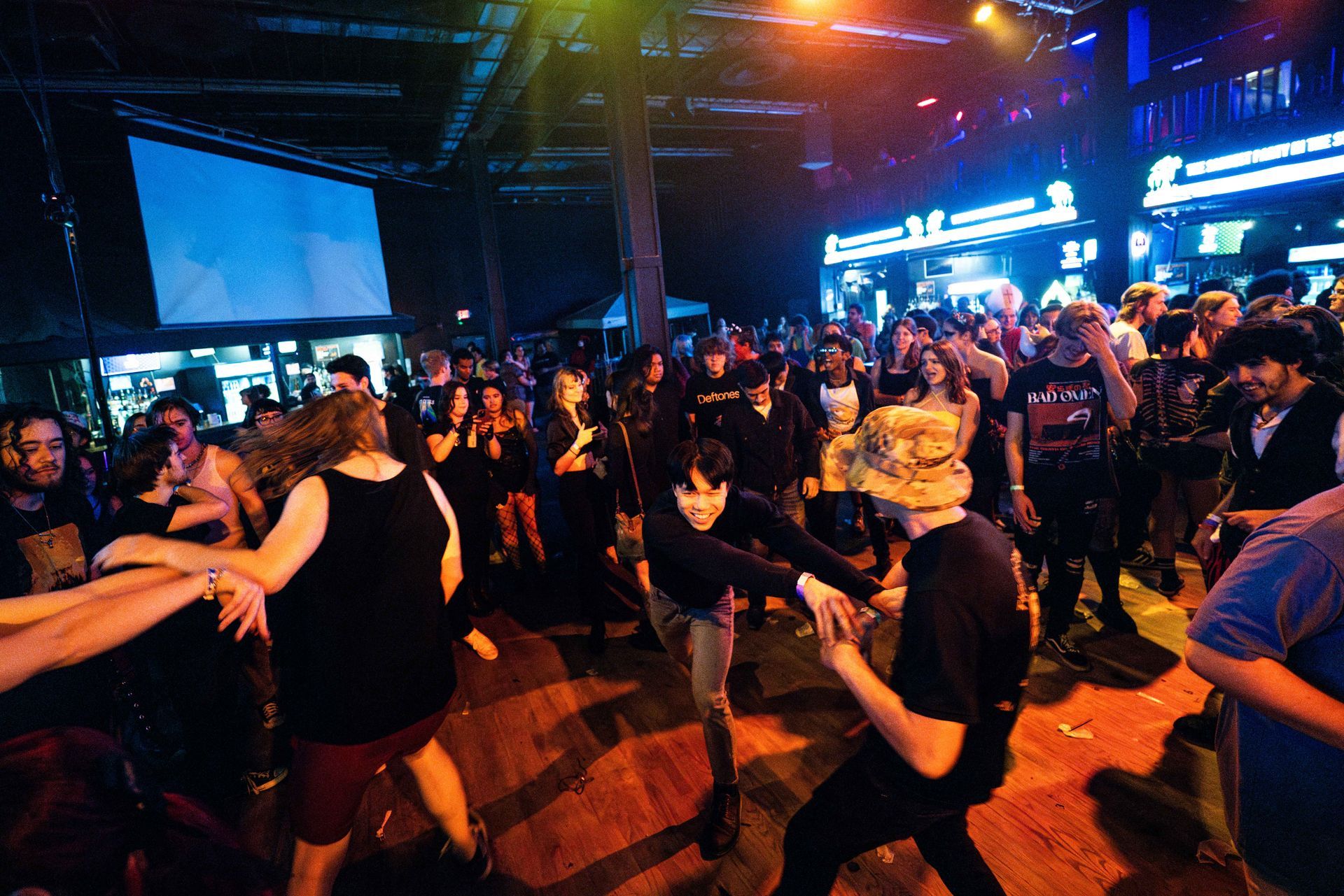 A large group of people are dancing in a dark room.