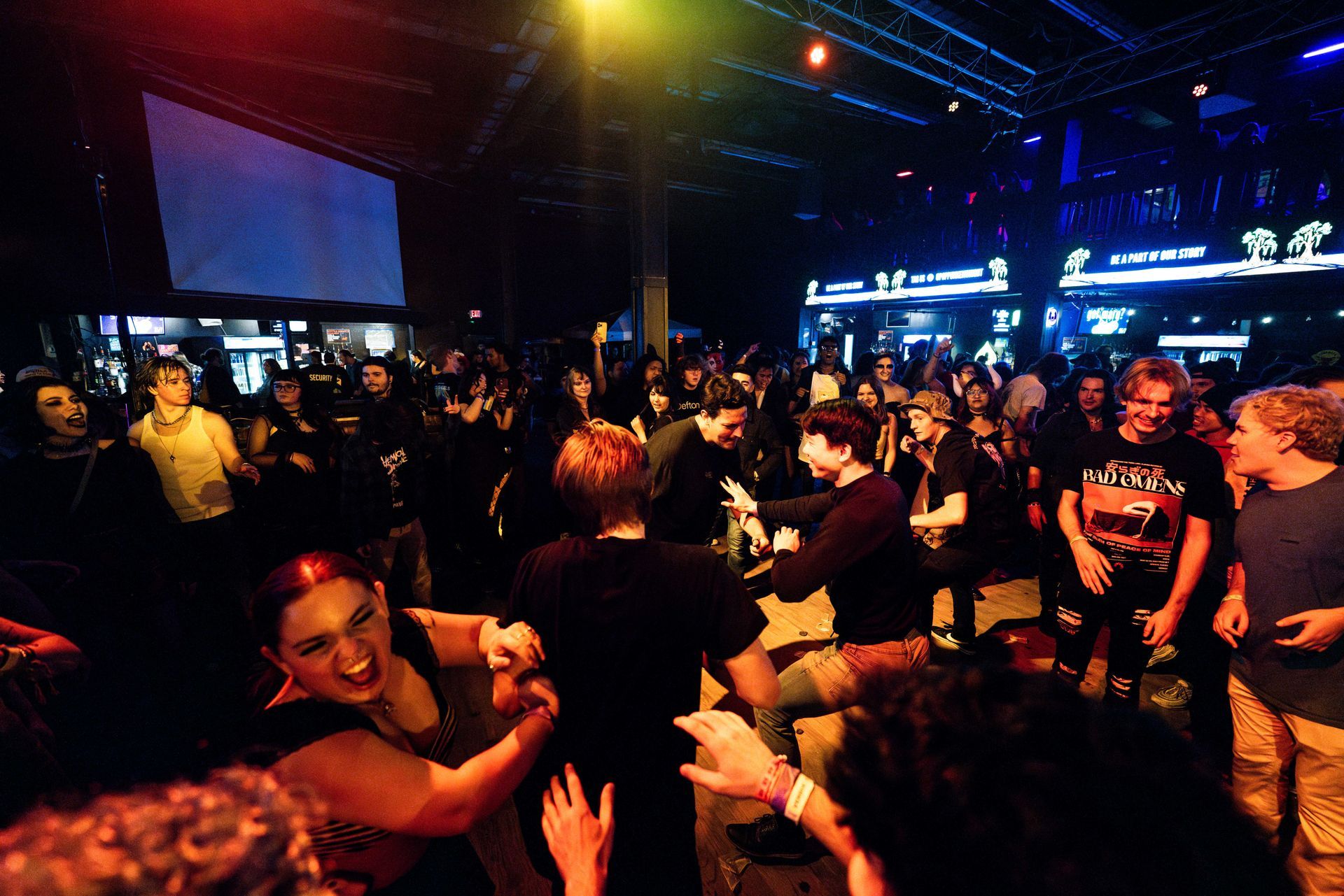 A crowd of people are dancing in a dark room.