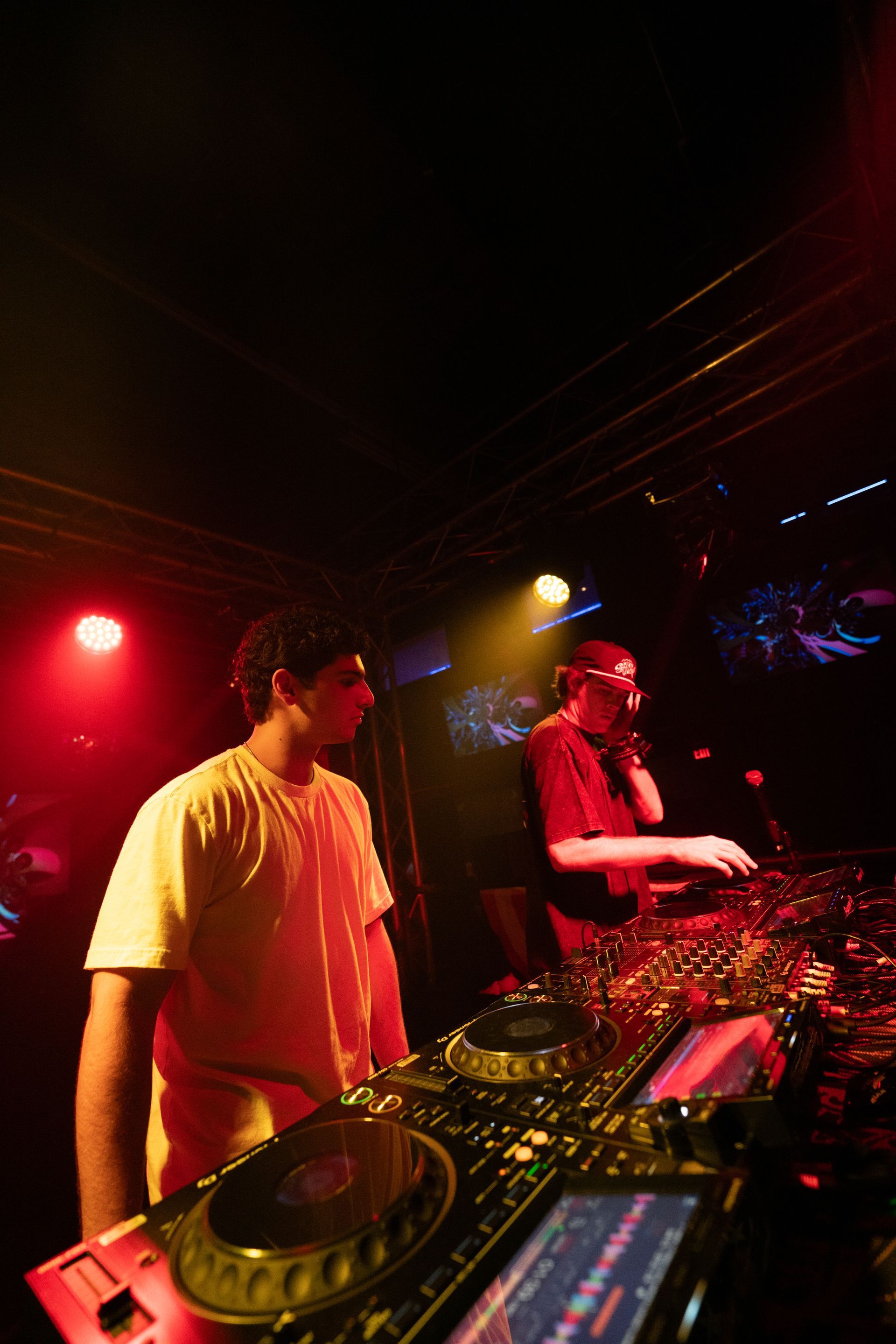 Two men are playing music on a stage in a dark room.