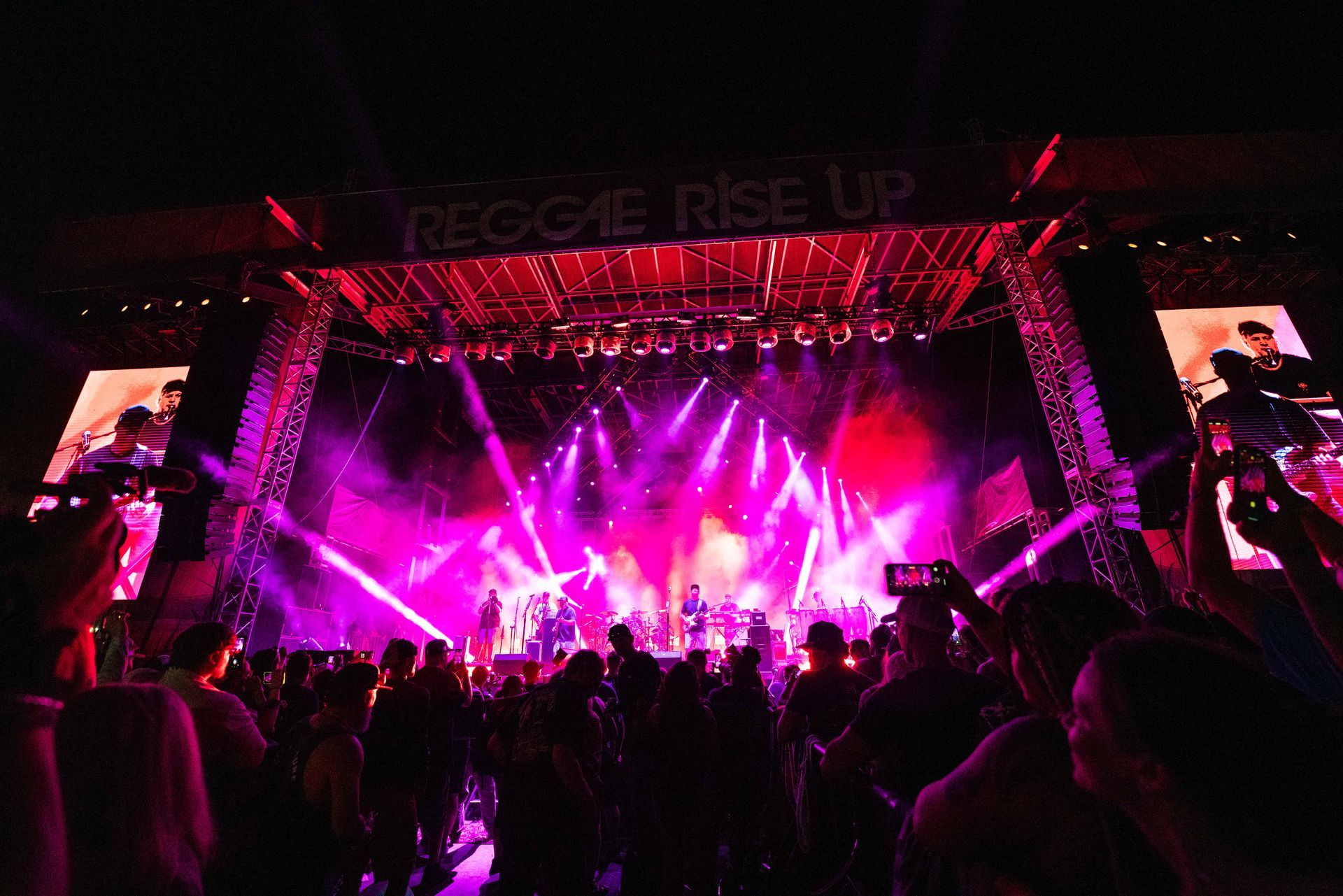 A crowd of people are standing in front of a stage at a concert.