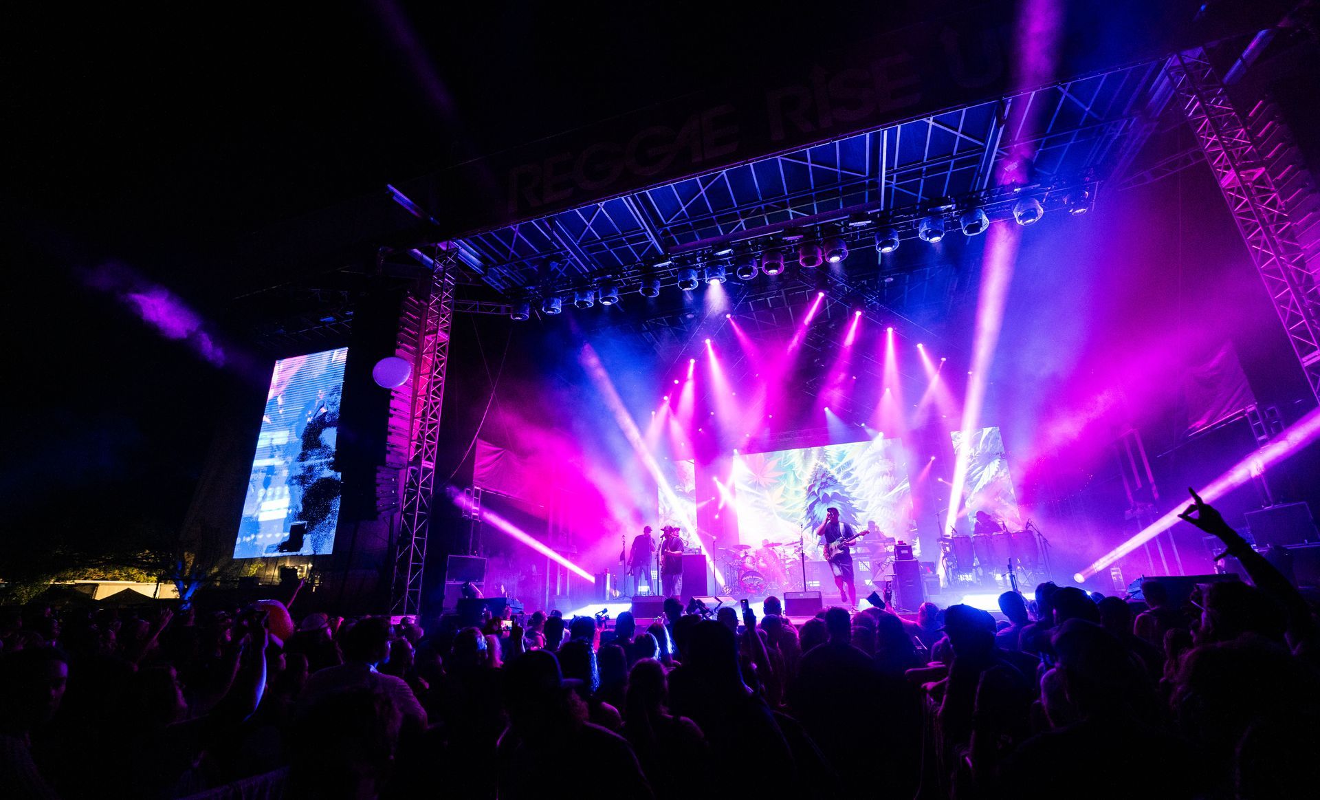 A crowd of people are watching a band perform on stage at a concert.