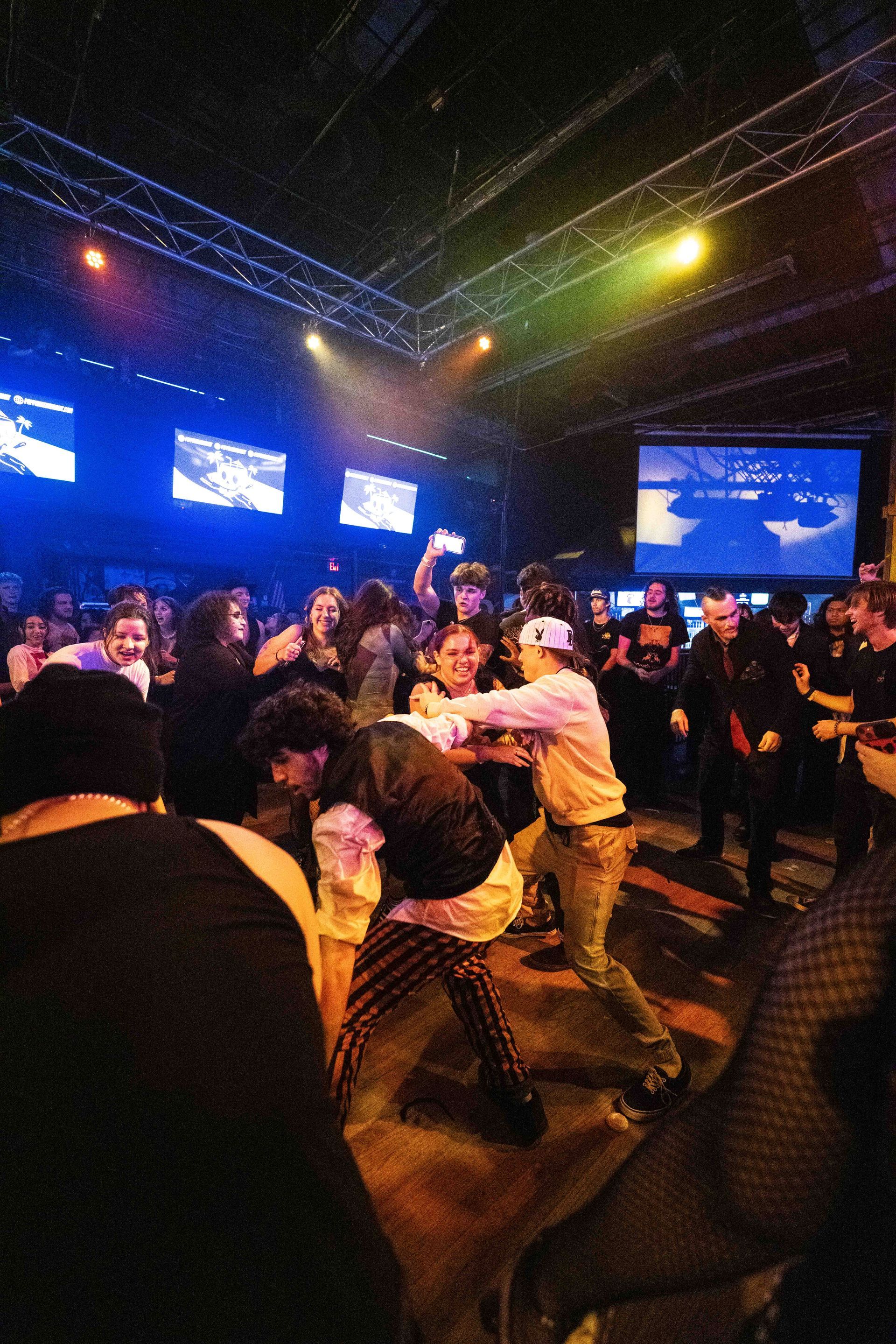 A crowd of people are dancing in a dark room.