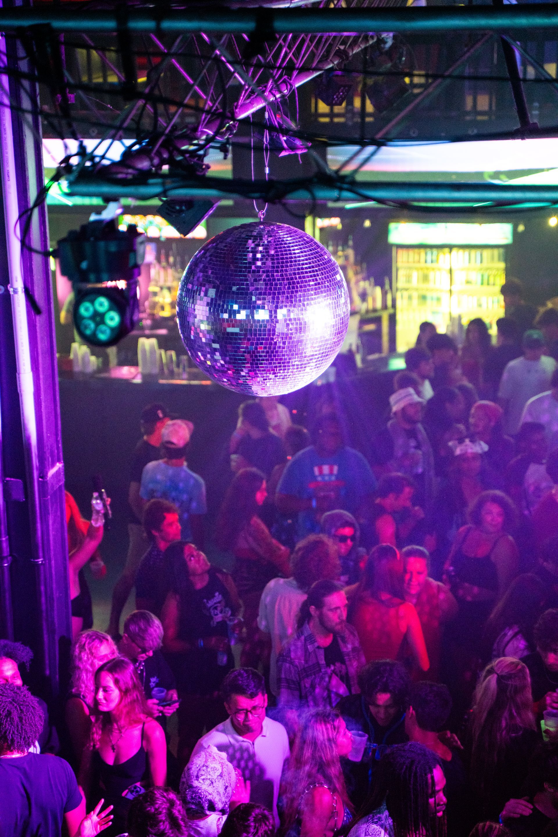 A disco ball hangs over a crowd of people at a party