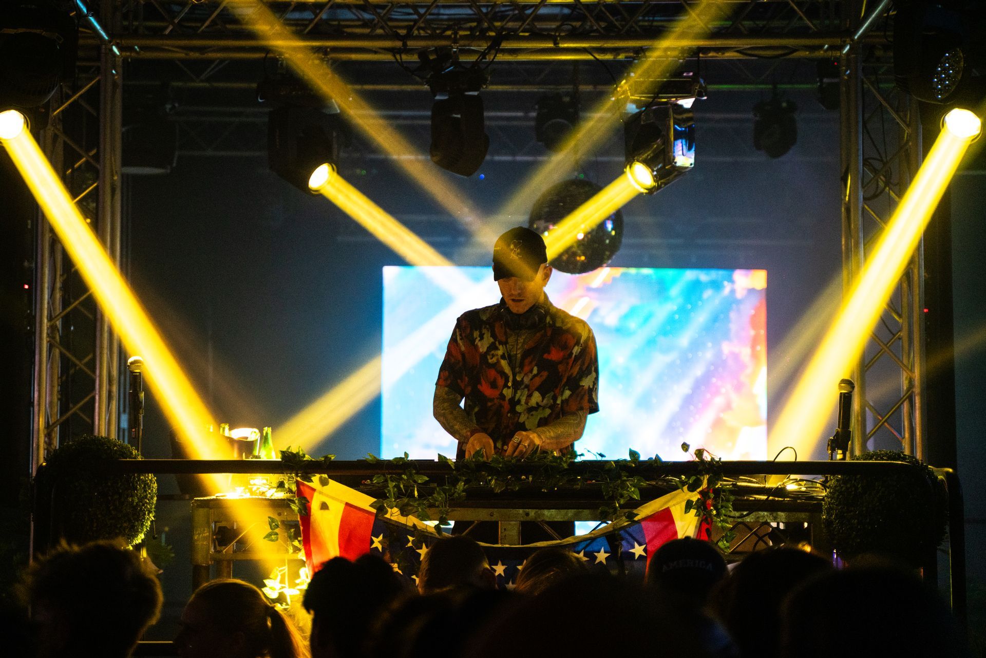 A man is playing a dj set on a stage in front of a crowd.