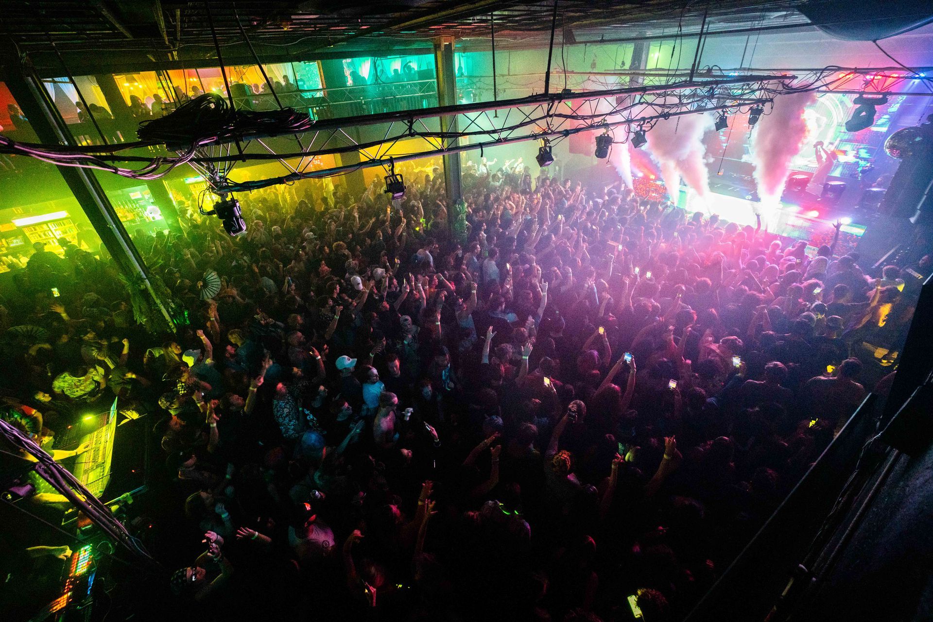 A large crowd of people are gathered in a dark room at a concert.