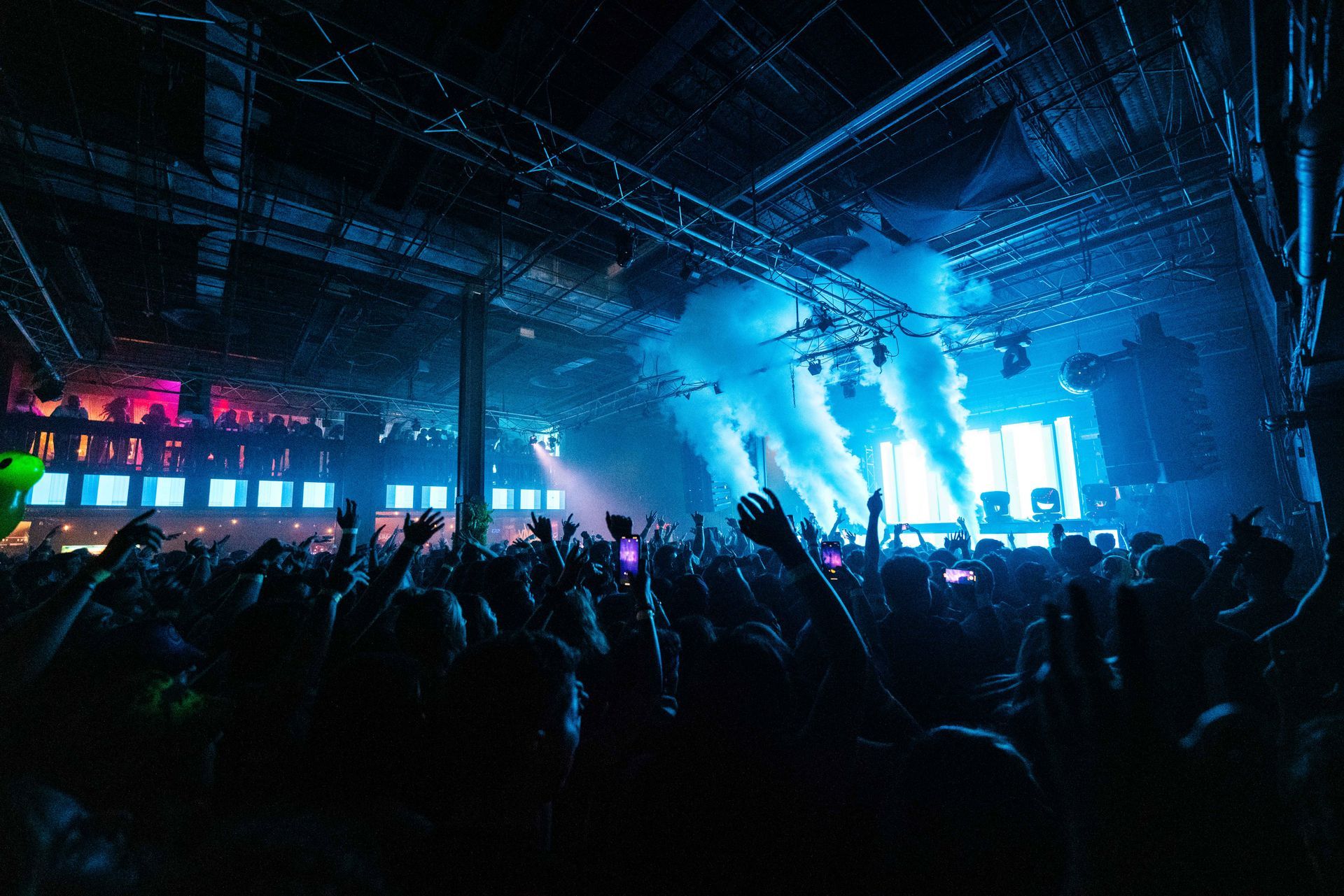 A crowd of people at a concert with their hands in the air