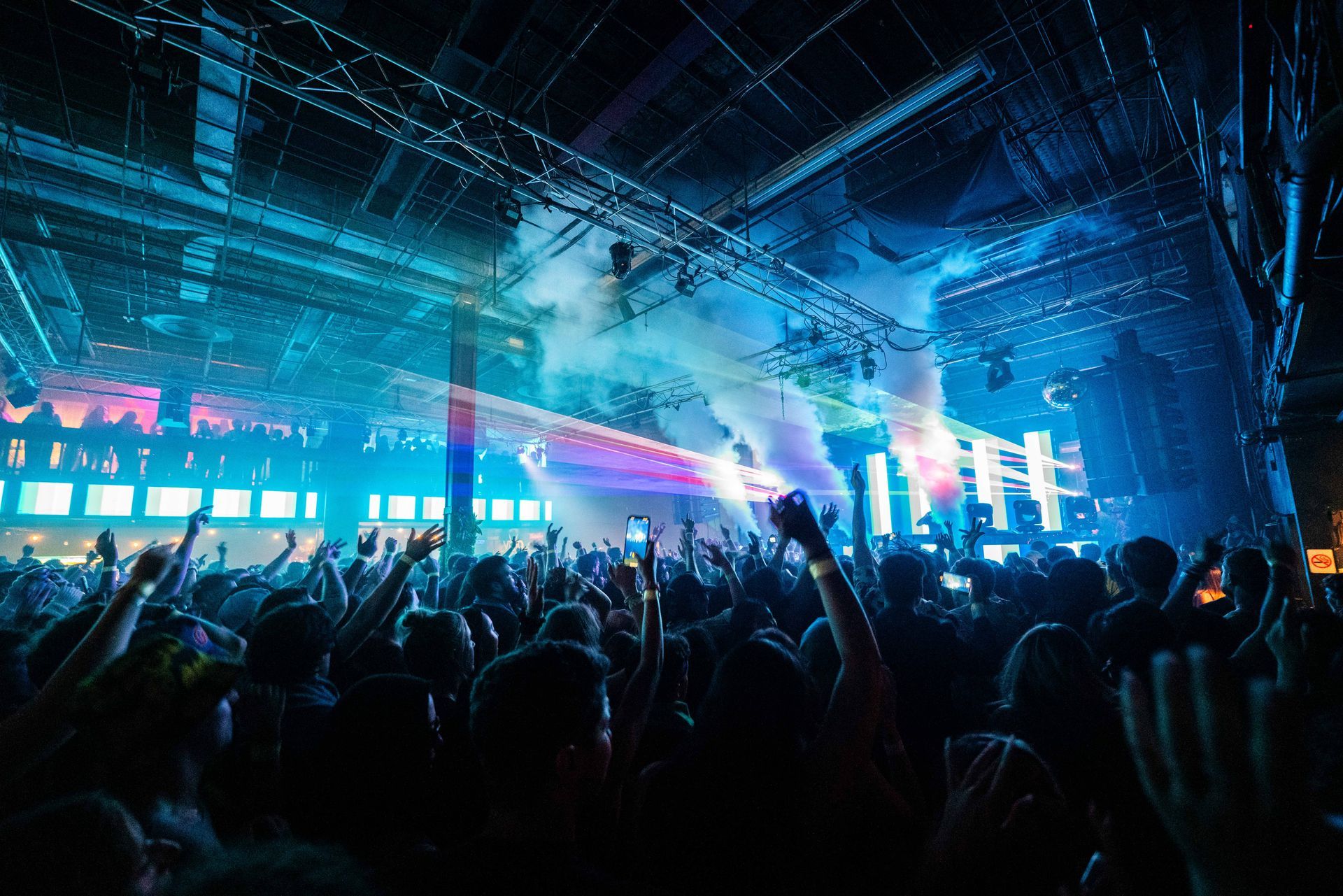 A crowd of people at a concert with their hands in the air.