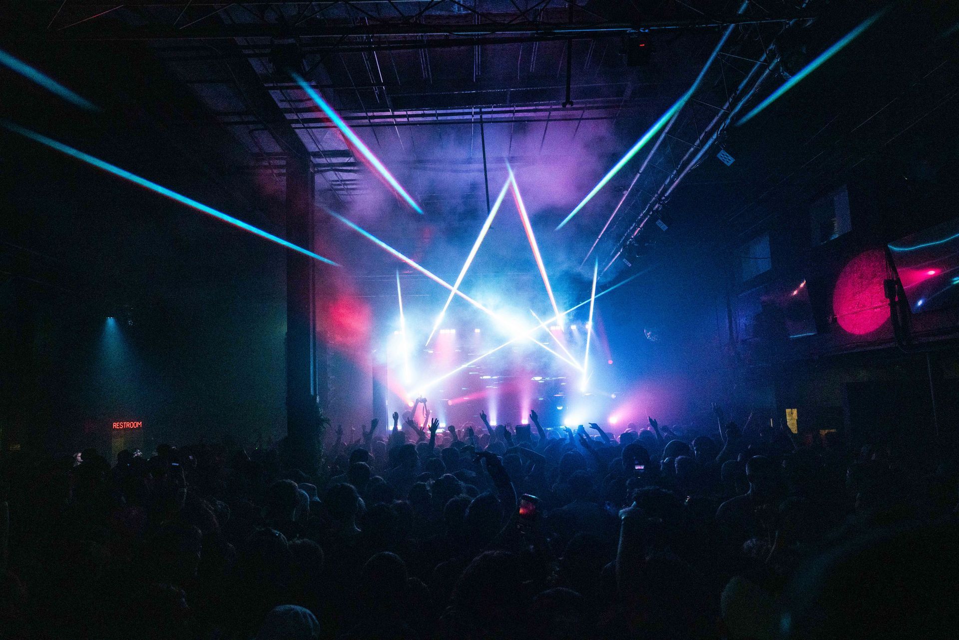 A crowd of people are watching a concert in a dark room.