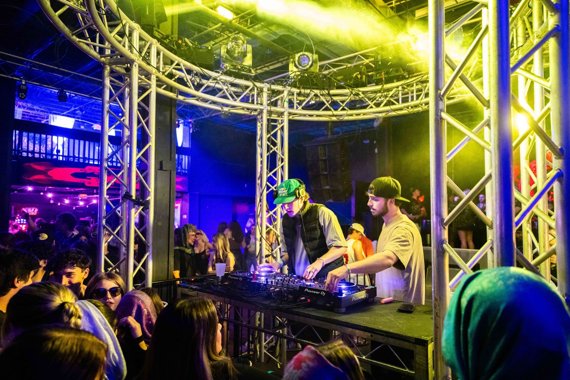 Two men are playing music on a stage in front of a crowd of people.