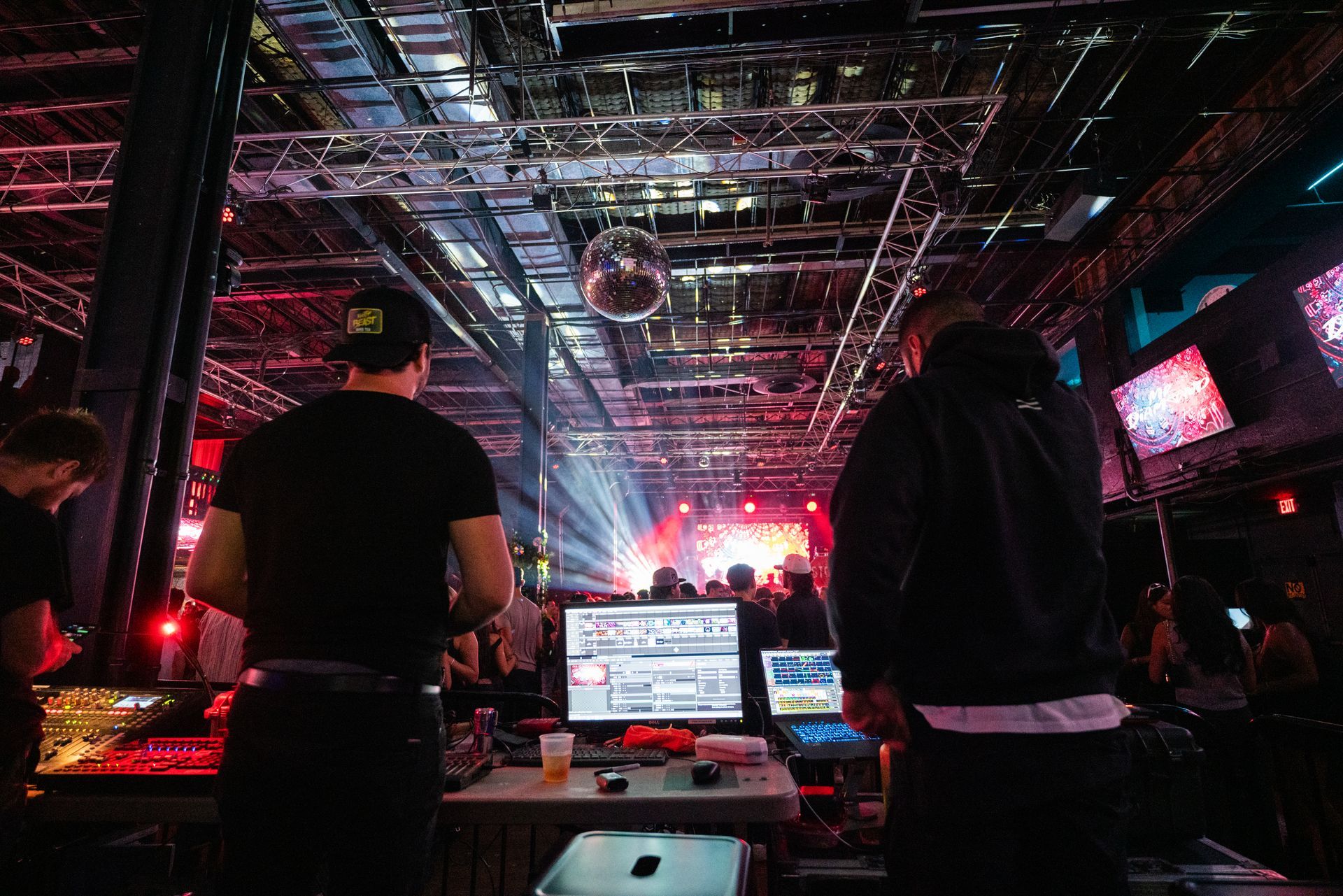 A group of people are standing in a dark room looking at a computer screen.